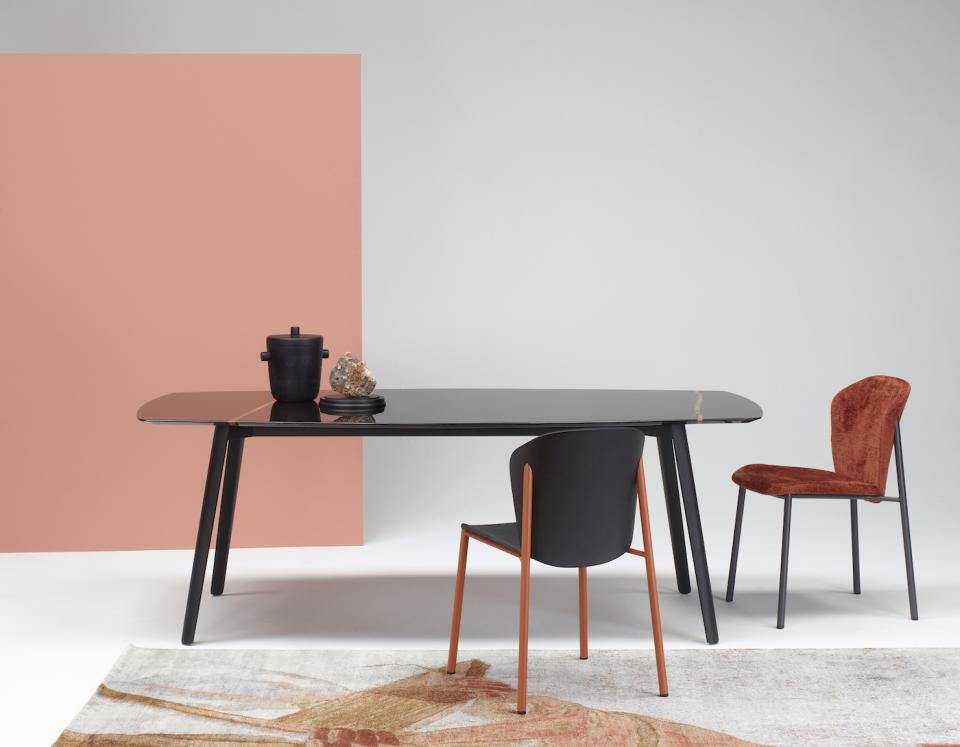 Elegant black dining table inspired by cuttlefish bone shape, with stylish chairs and decorative accessories in a modern interior setting.