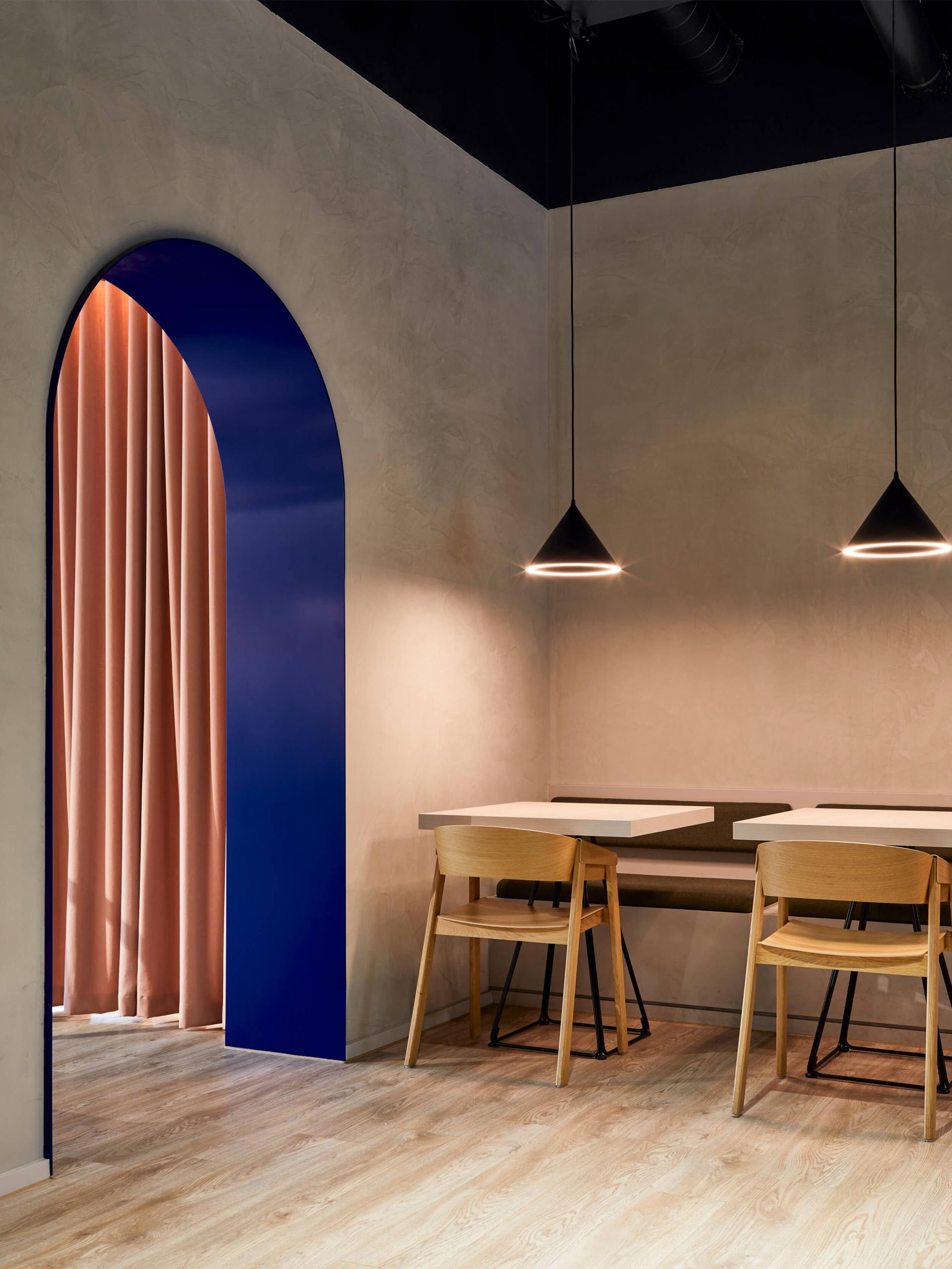 Cozy interior design featuring a blue archway, pink curtains, and modern wooden furniture in a well-lit space.