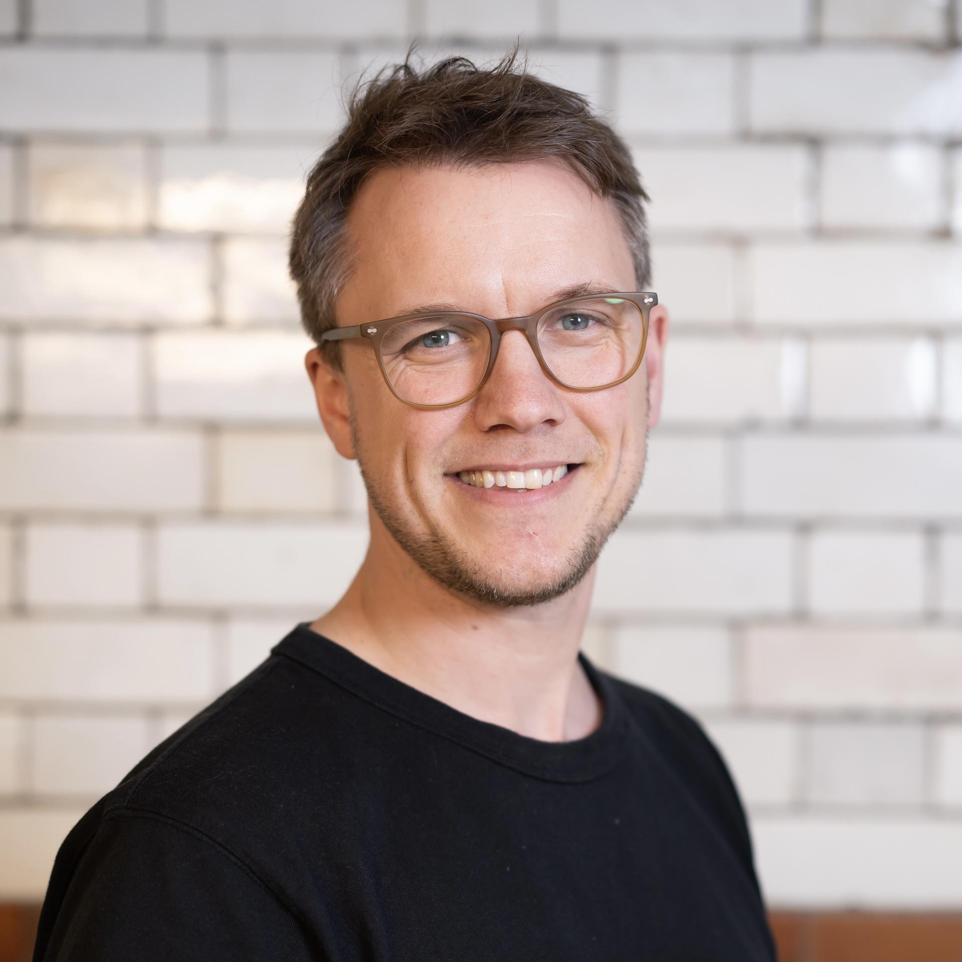 Smiling professional in a black shirt, representing the impact of technology in the workplace.