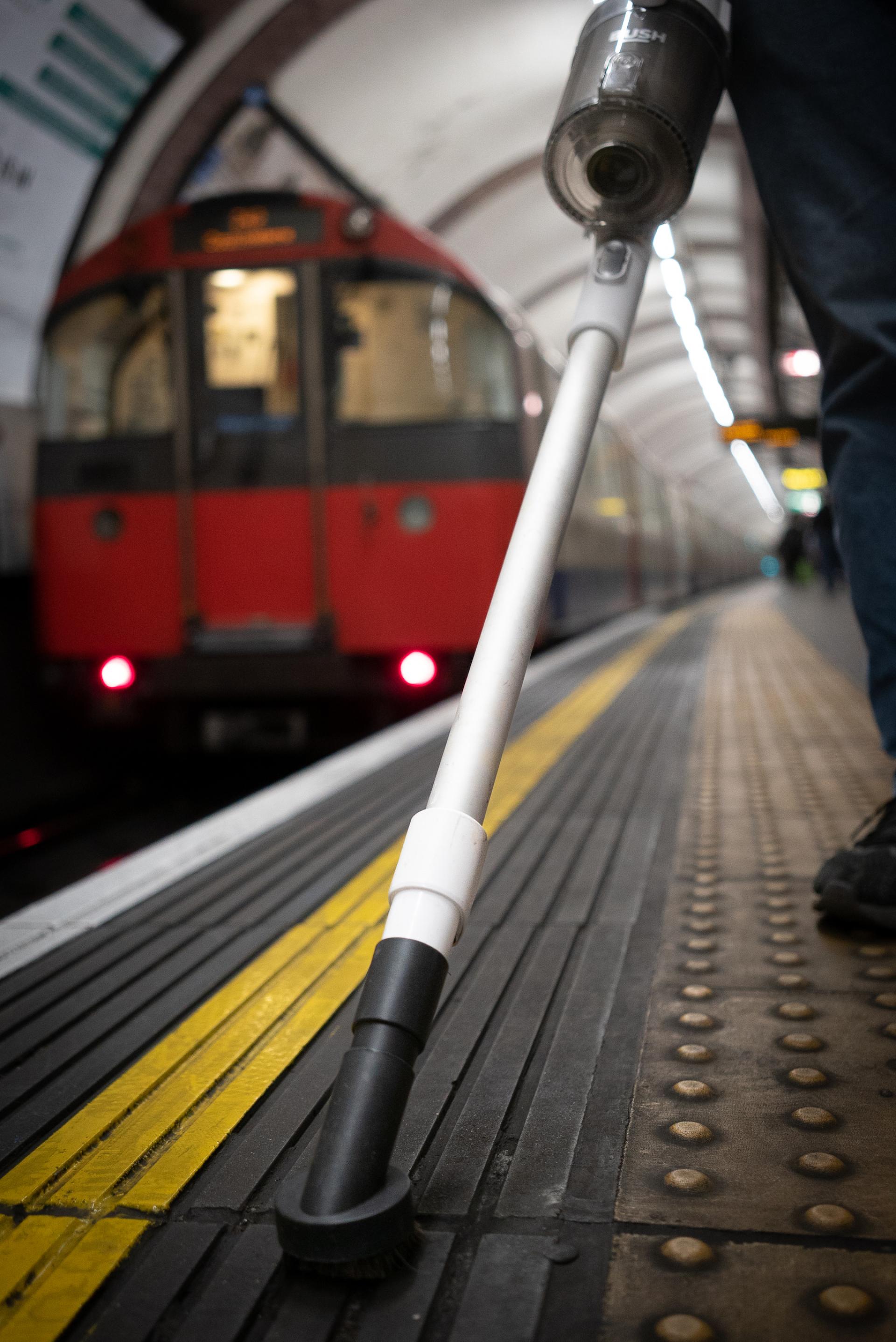 Innovative vacuum cleaner on London Underground platform, highlighting Jeffrey Miller's project on transforming waste into tiles.