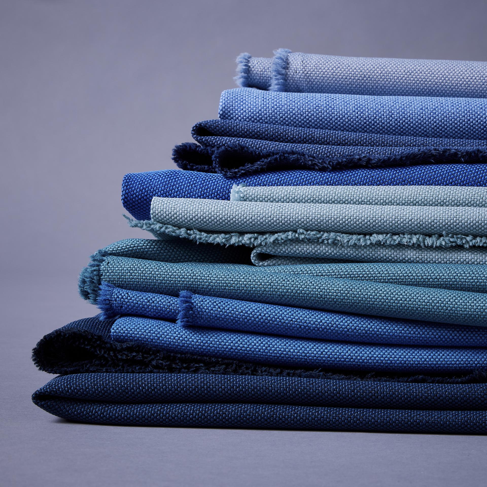 Sustainably sourced blue fabrics stacked elegantly, showcasing Camira's commitment to combating marine plastic pollution.