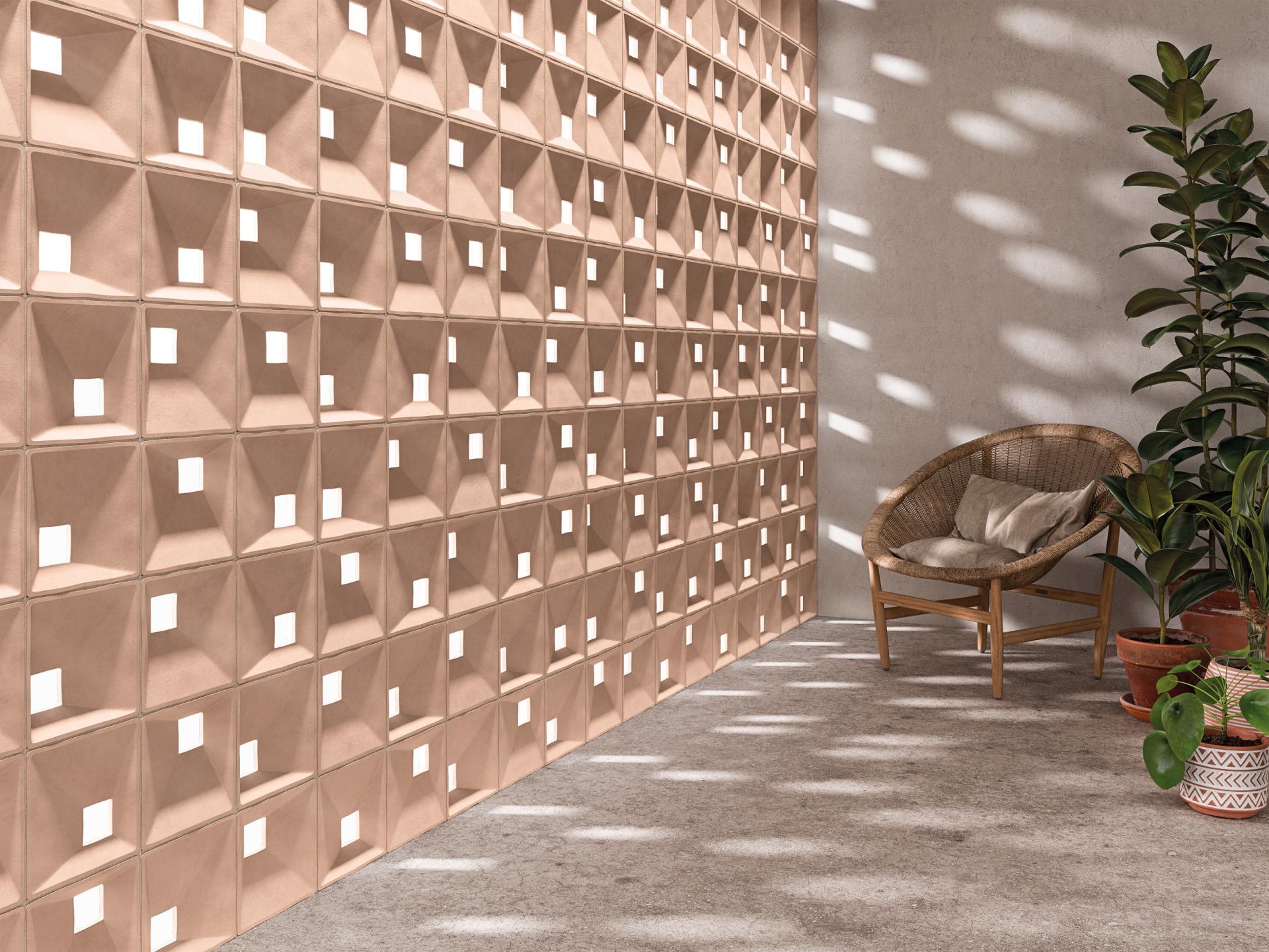 Modern interior featuring a textured wall with square cutouts, rattan chair, and vibrant greenery, showcasing innovative tile design.