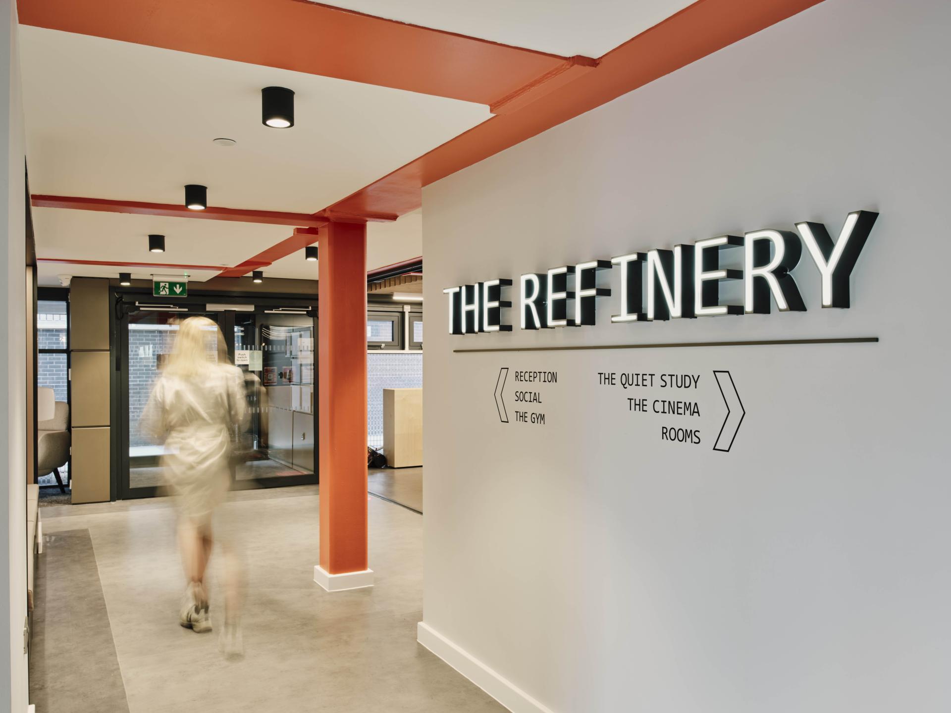 Modern hallway featuring signage for The Refinery student accommodation, highlighting social, study, and cinema spaces in Leeds.