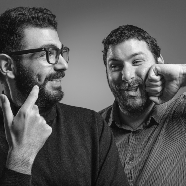 Two bearded men share a lighthearted moment, showcasing the creative spirit of Taner's Sons Design Studio.