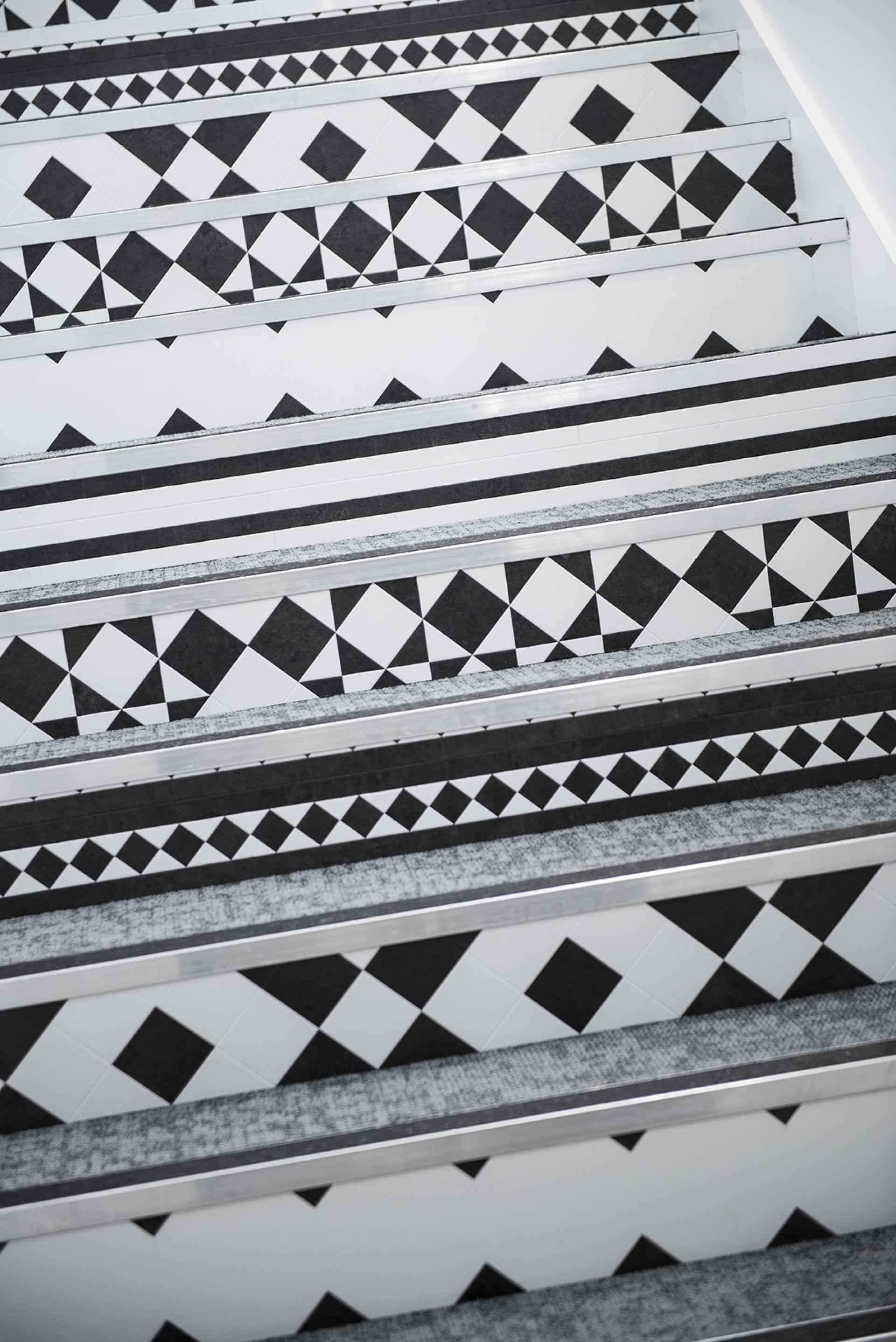 Geometric black and white patterned flooring on stairs, showcasing the industrial style of Karndean Heritage Collection.