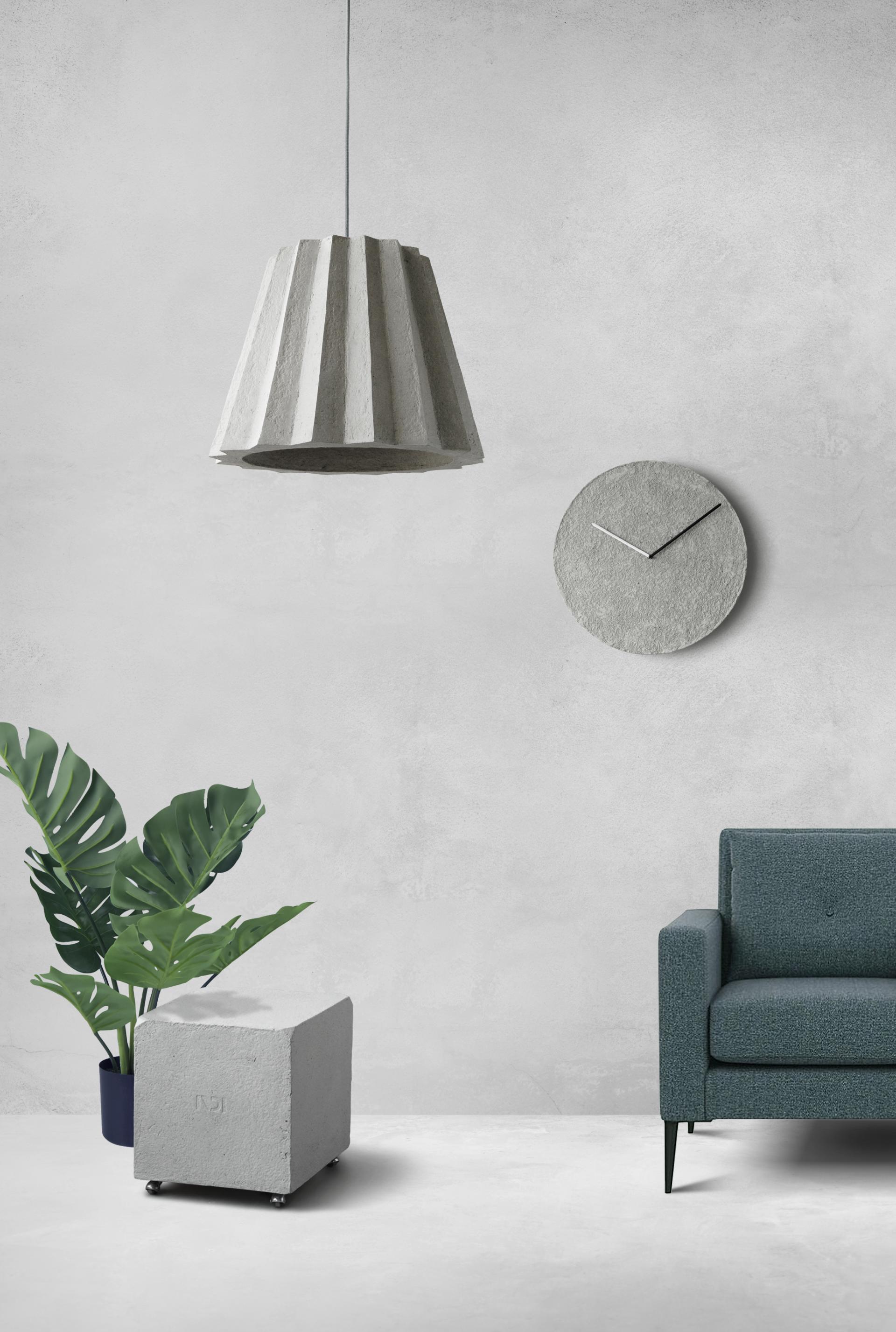 Innovative interior design featuring a concrete lamp, clock, plant, and stylish sofa in a minimalist setting.