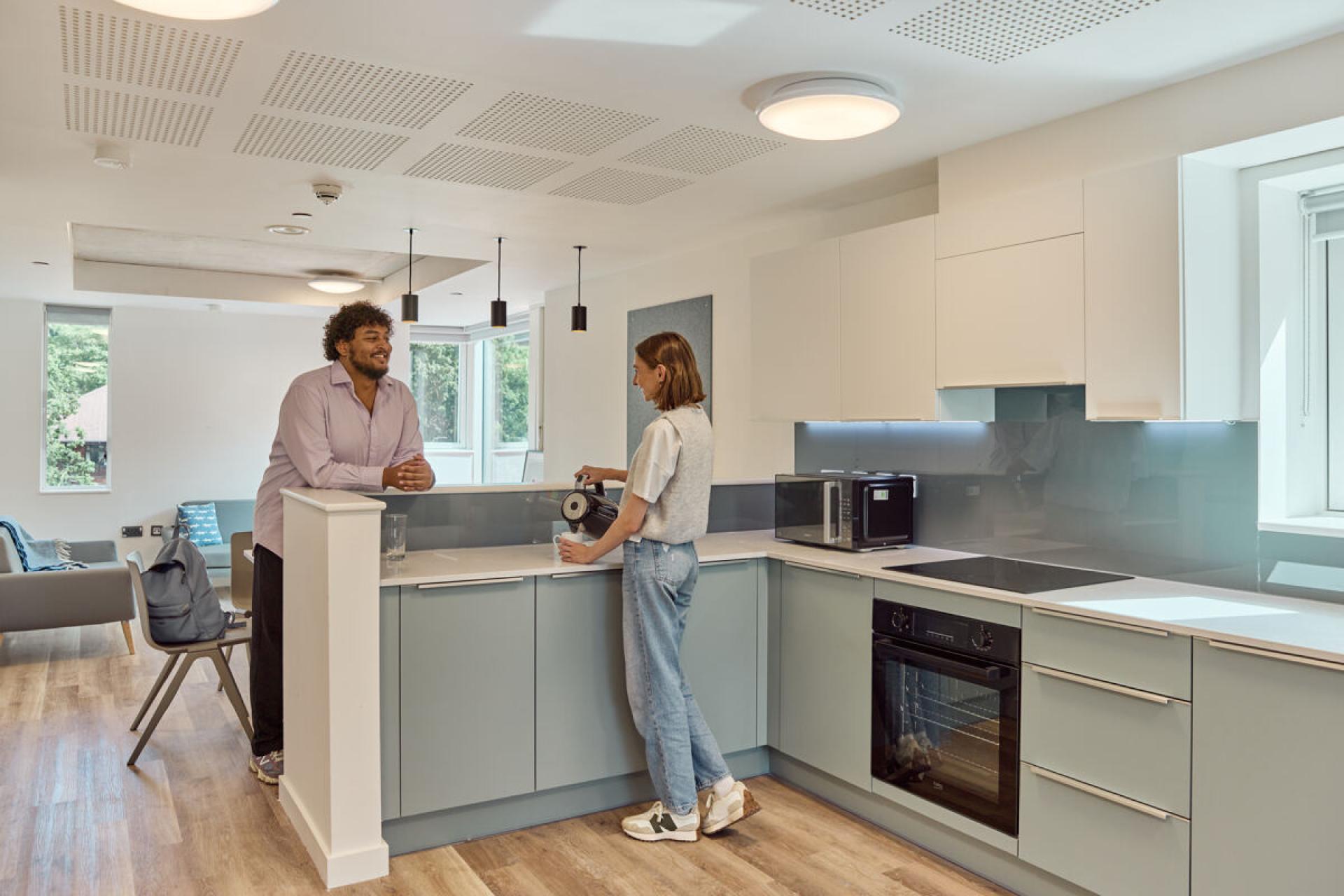 Students interacting in a modern kitchen, showcasing the vibrant student accommodation at Oxford Brookes University with stylish design and communal space.