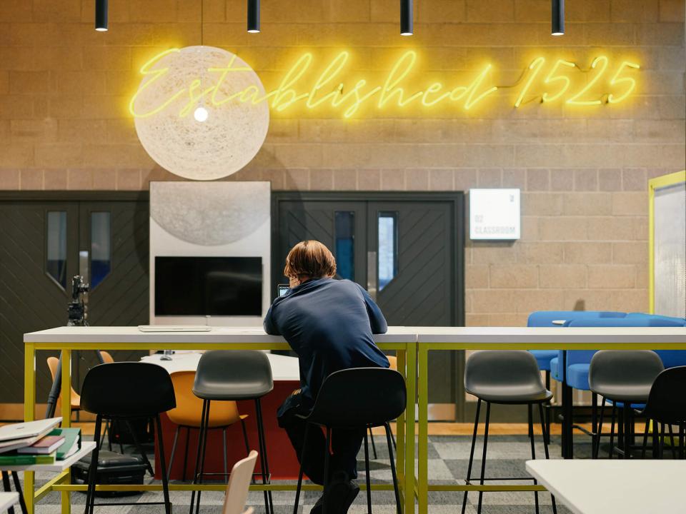 Stylish interior of Sedbergh School's Queens Hall featuring neon signage, modern seating, and vibrant colors.