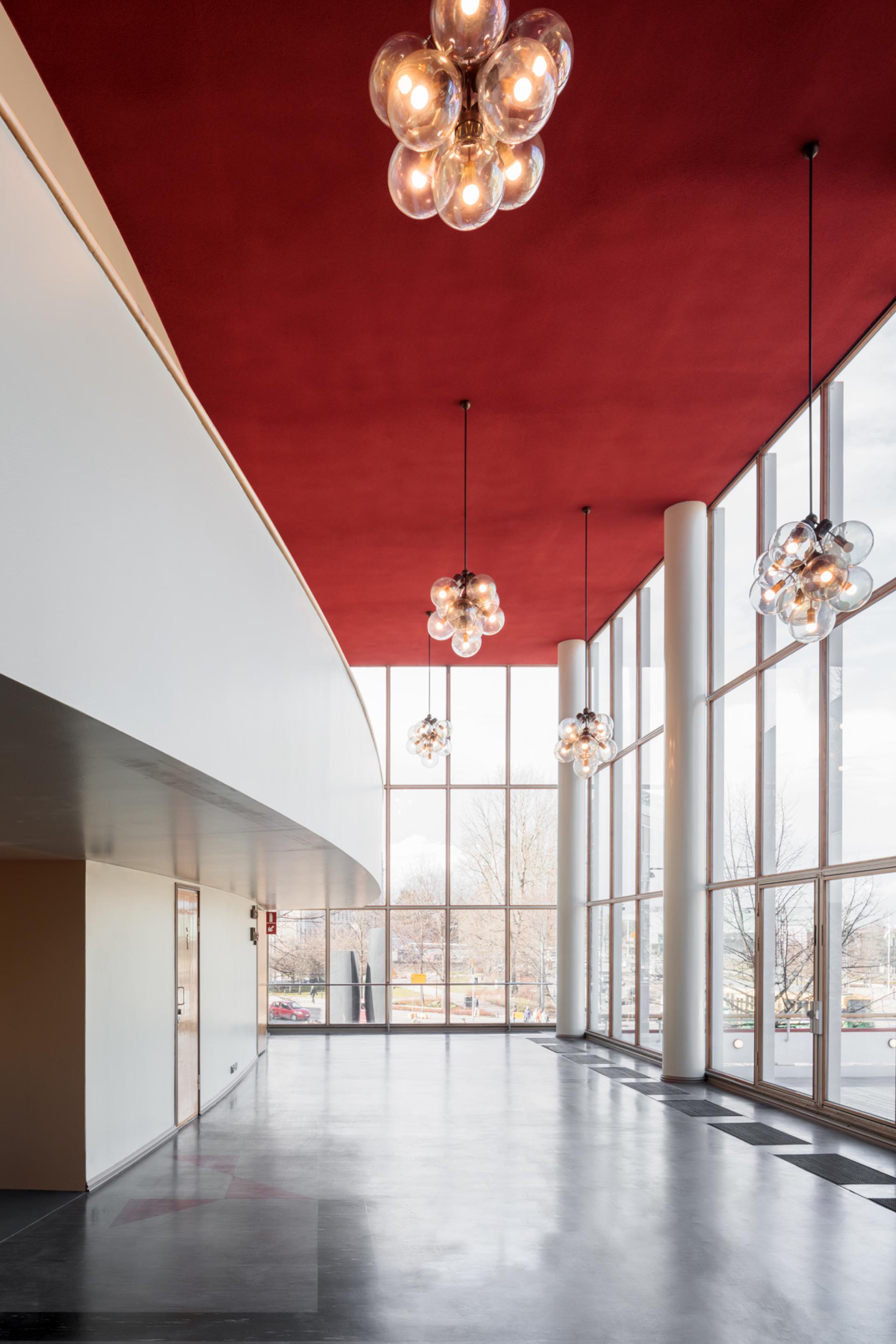 Modern interior of Helsinki's art museum featuring a red ceiling and contemporary lighting fixtures.