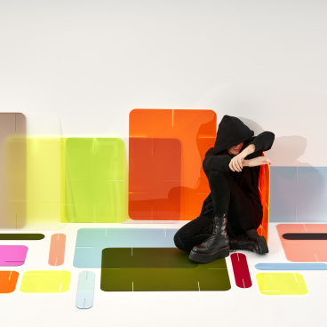 Colorful translucent panels surround a person sitting on the floor, showcasing Zahava Elenberg's innovative Clikclax design solution.
