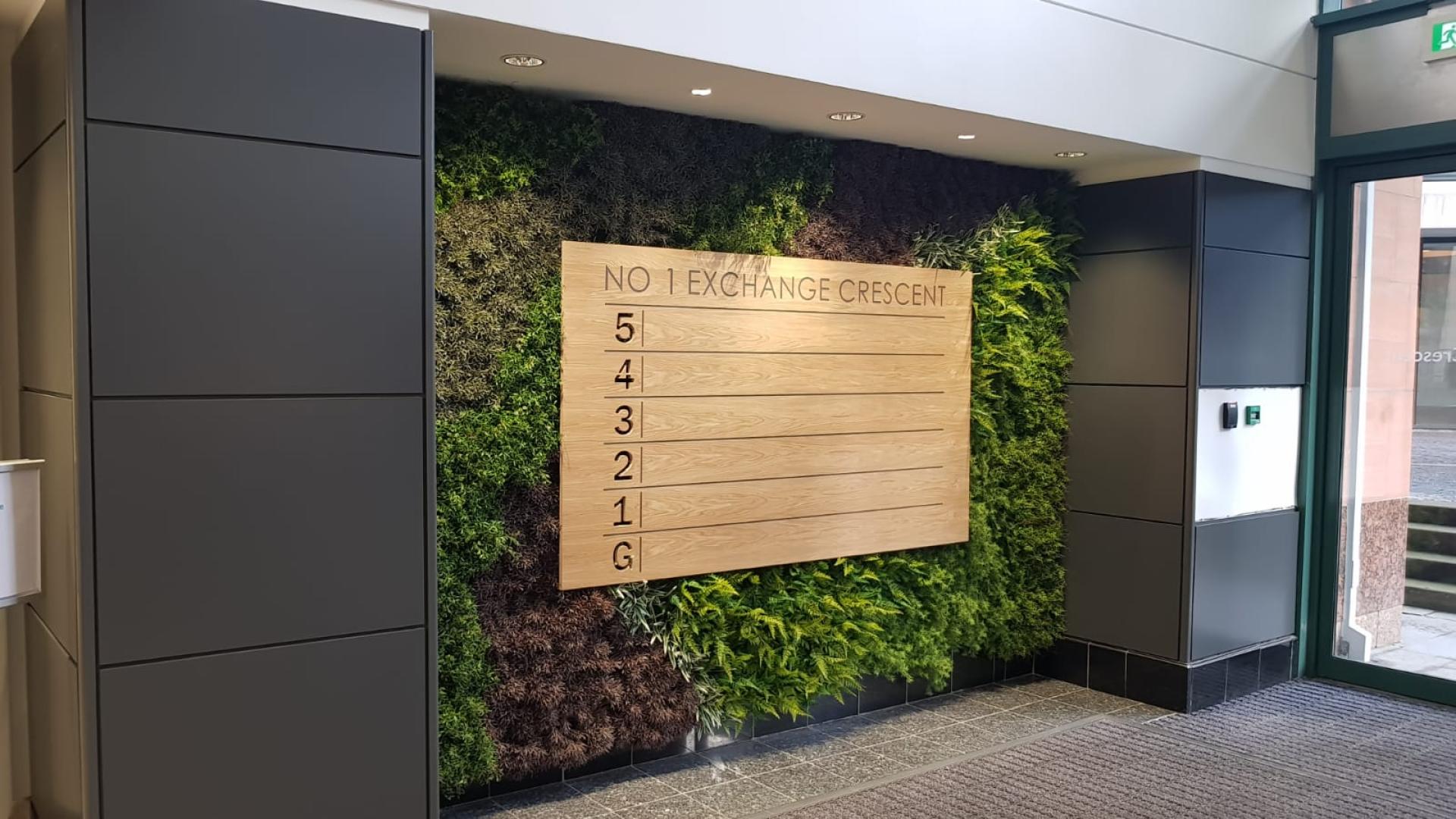 Green wall installation featuring wooden directory sign at No 1 Exchange Crescent, highlighting biophilic design principles.