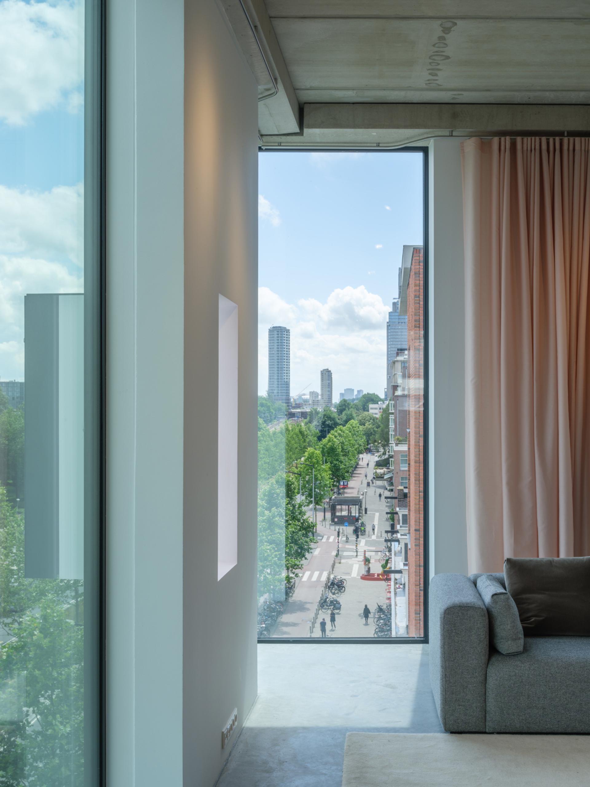 Modern studio interior by thonik, featuring large windows showcasing views of Wibautstraat, Amsterdam, with lush greenery outside.