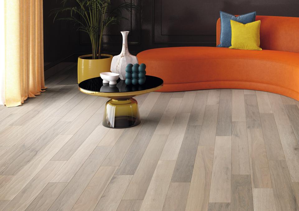 Stylish living room featuring sustainable flooring, an orange couch, decorative plants, and a modern coffee table arrangement.