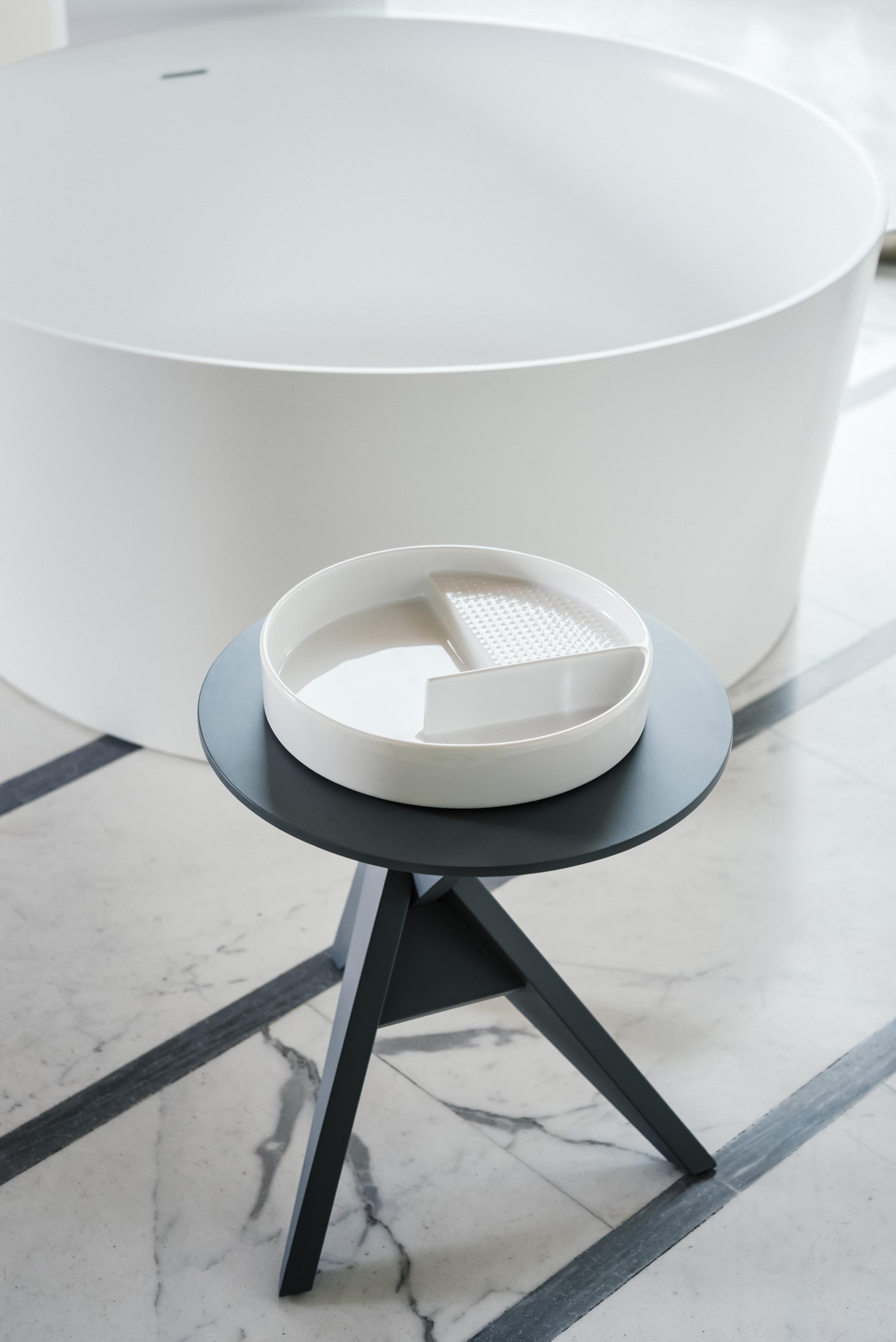 Stylish modern bathtub with a minimalist side table and elegant white dish, highlighting LAUFEN's design aesthetic.