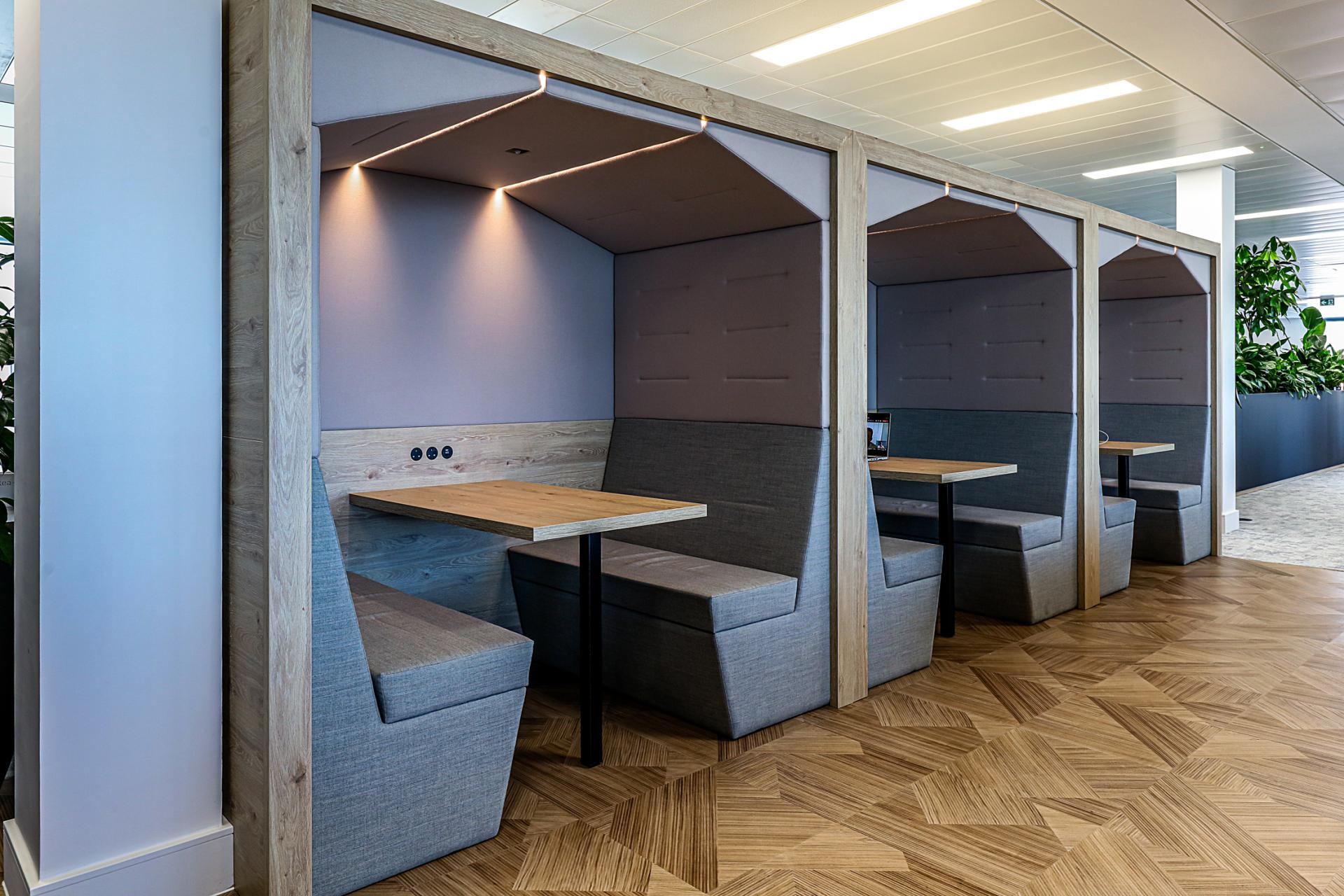 Modern office booths featuring wooden frames, plush seating, and ambient lighting at Domestic & General's Wimbledon headquarters.