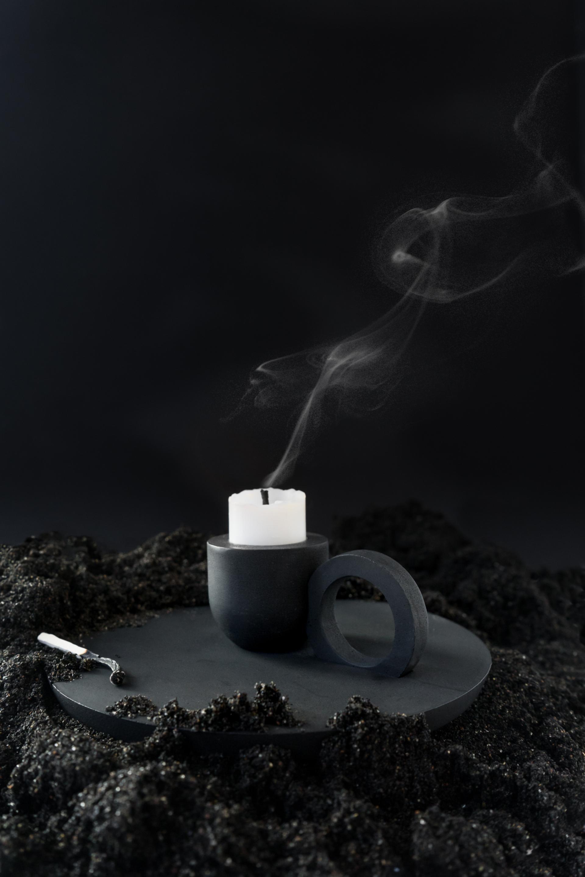 Elegant black candle holder with a lit white candle, surrounded by textured black material, showcasing Glasgow's creative craft scene.