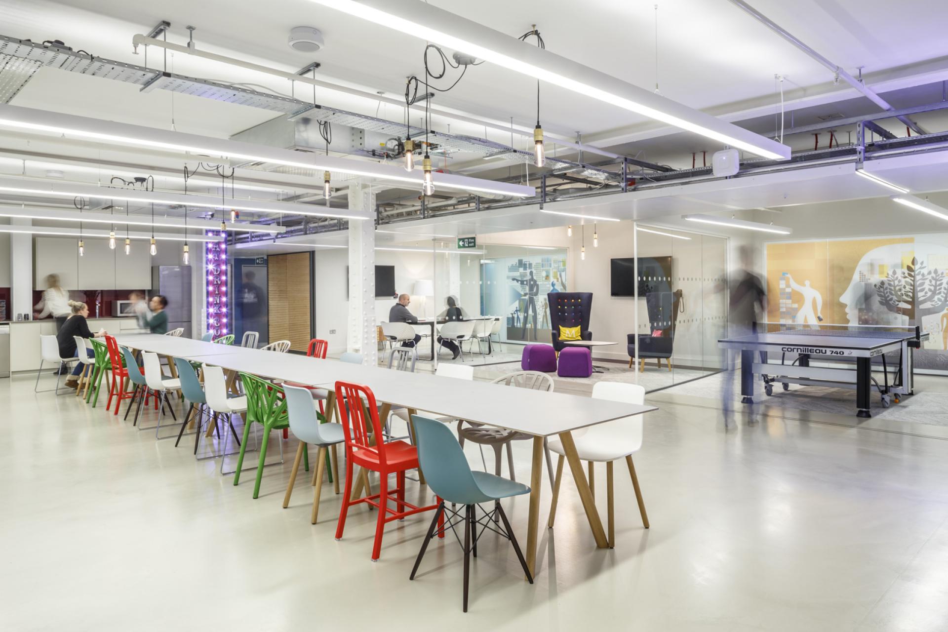 Modern open-plan workspace featuring colorful chairs, collaborative areas, and playful design elements promoting creativity and interaction.