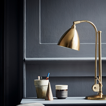 Stylish workspace featuring a brass desk lamp, decorative containers, and a modern color palette for productivity.