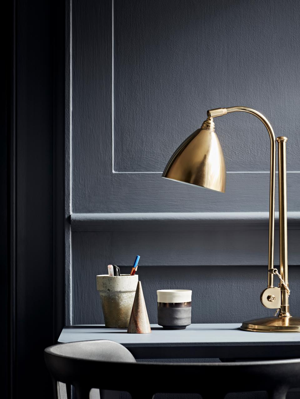 Stylish workspace featuring a brass desk lamp, decorative containers, and a modern color palette for productivity.