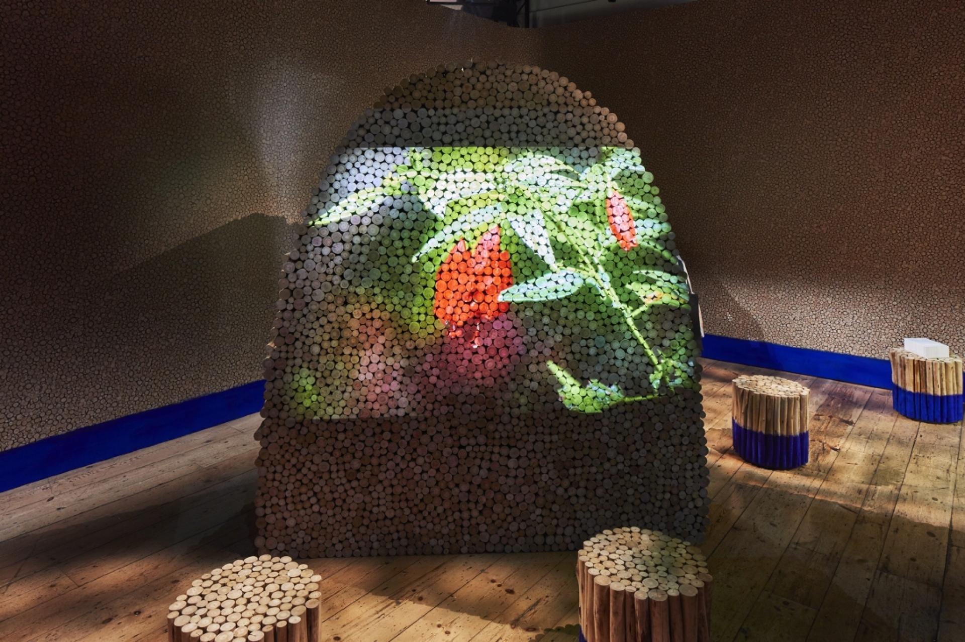 Sustainable design installation featuring a vibrant floral projection on a textured wall made of wooden materials.