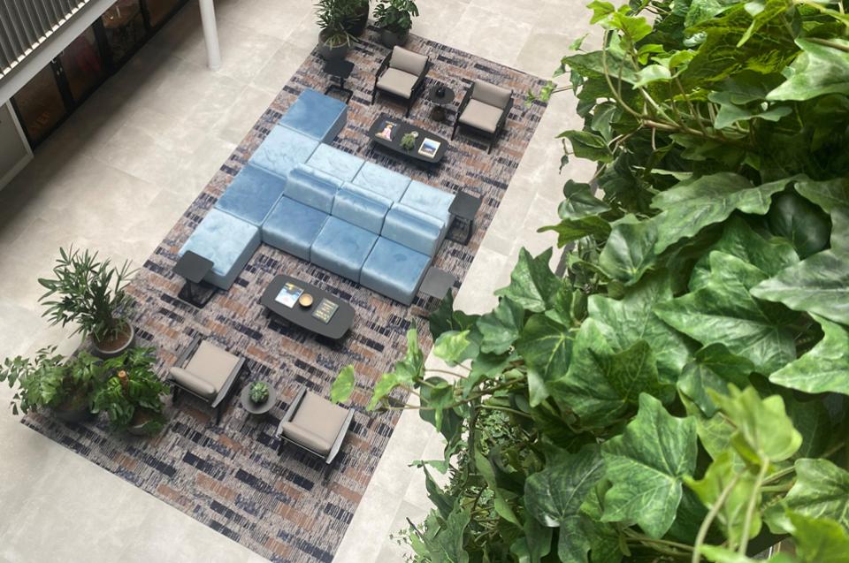 Bespoke rug design showcased in a modern lounge area of Sevendale House, featuring lush plants and contemporary seating.