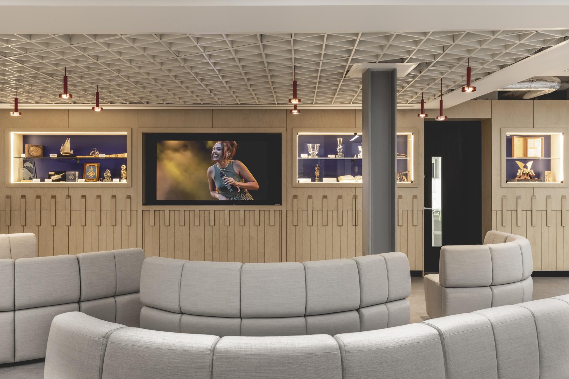 Modern lounge area in PRS for Music's HQ, featuring curved seating, music-themed decor, and multimedia displays.