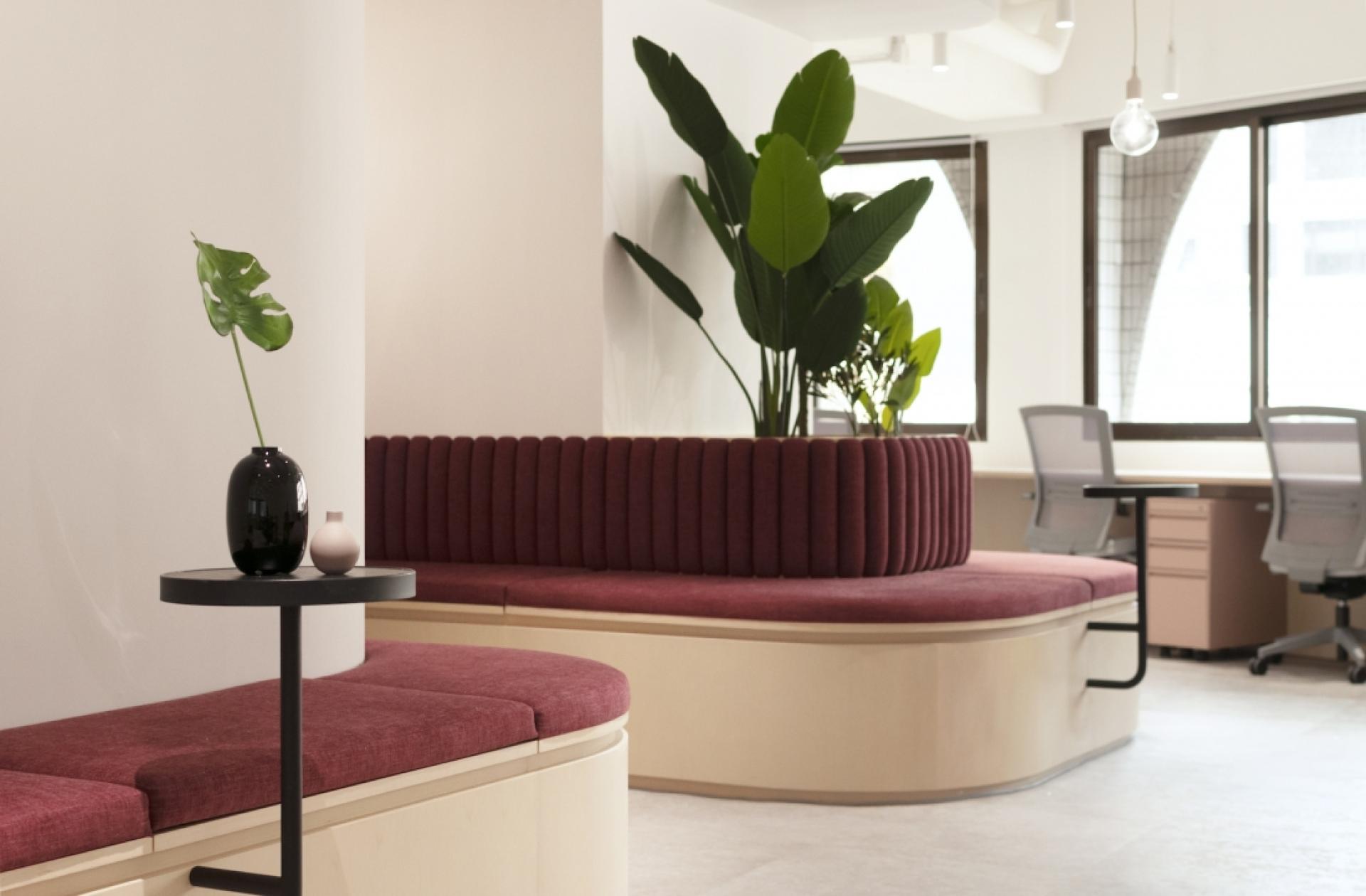 Modern workplace design featuring stylish seating, greenery, and natural light in a collaborative office environment.