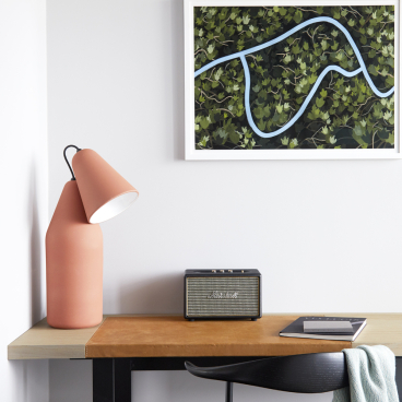 Stylish workspace featuring a modern lamp, vintage speaker, artwork, and a cozy chair at PURO Kraków Kazimierz.