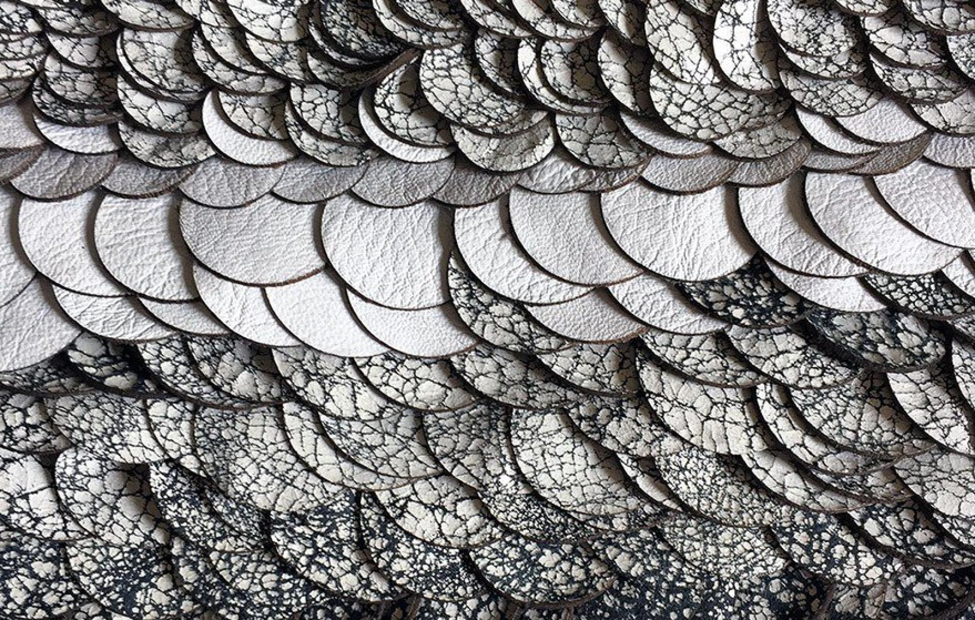 Detailed textured surface featuring layered circular leather pieces, showcasing innovative design for the Surface Design Show.