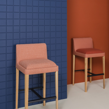 Stylish Kyoto collection bar stools in orange upholstery against a modern blue and orange wall backdrop.