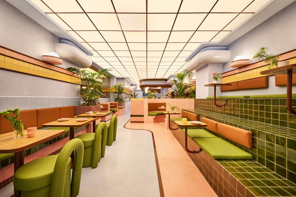 Vibrant interior of a Barcelona ice cream parlour featuring a reimagined Art Deco design with colorful seating and plants.