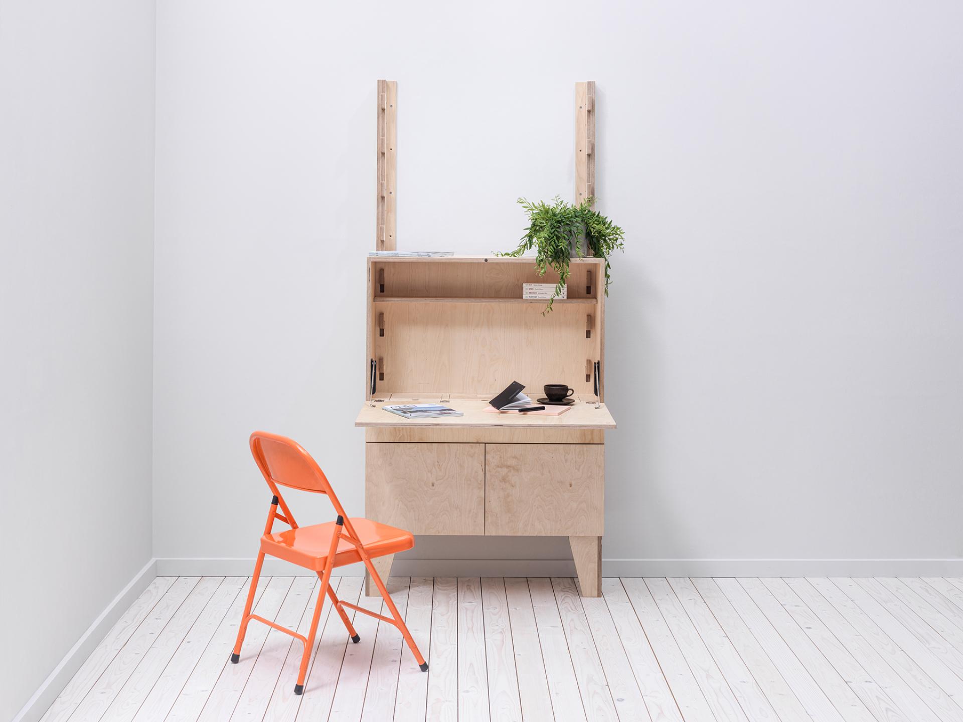 Bespoke modular workspace featuring a minimalist wooden desk with an orange chair and decorative plant in a modern setting.