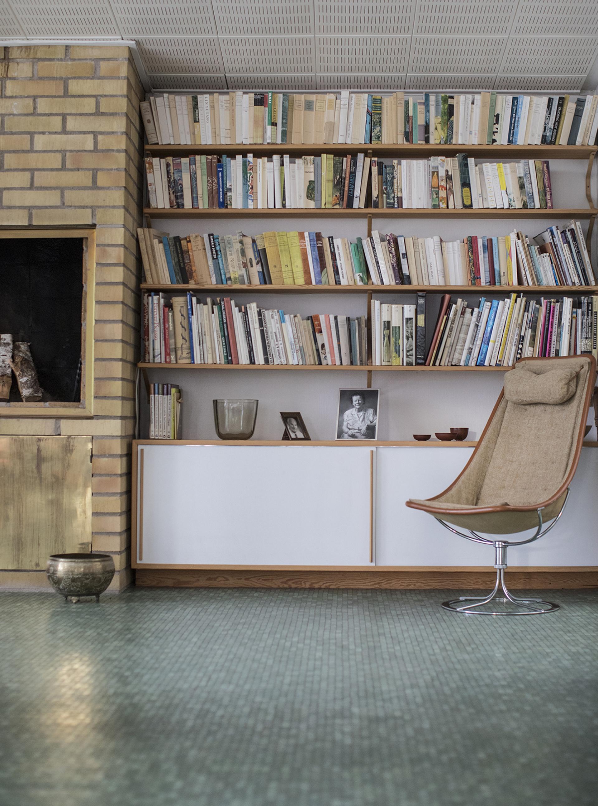 Cozy interior of Karin and Bruno Mathsson's home, featuring a bookshelf, designer chair, and decorative items.