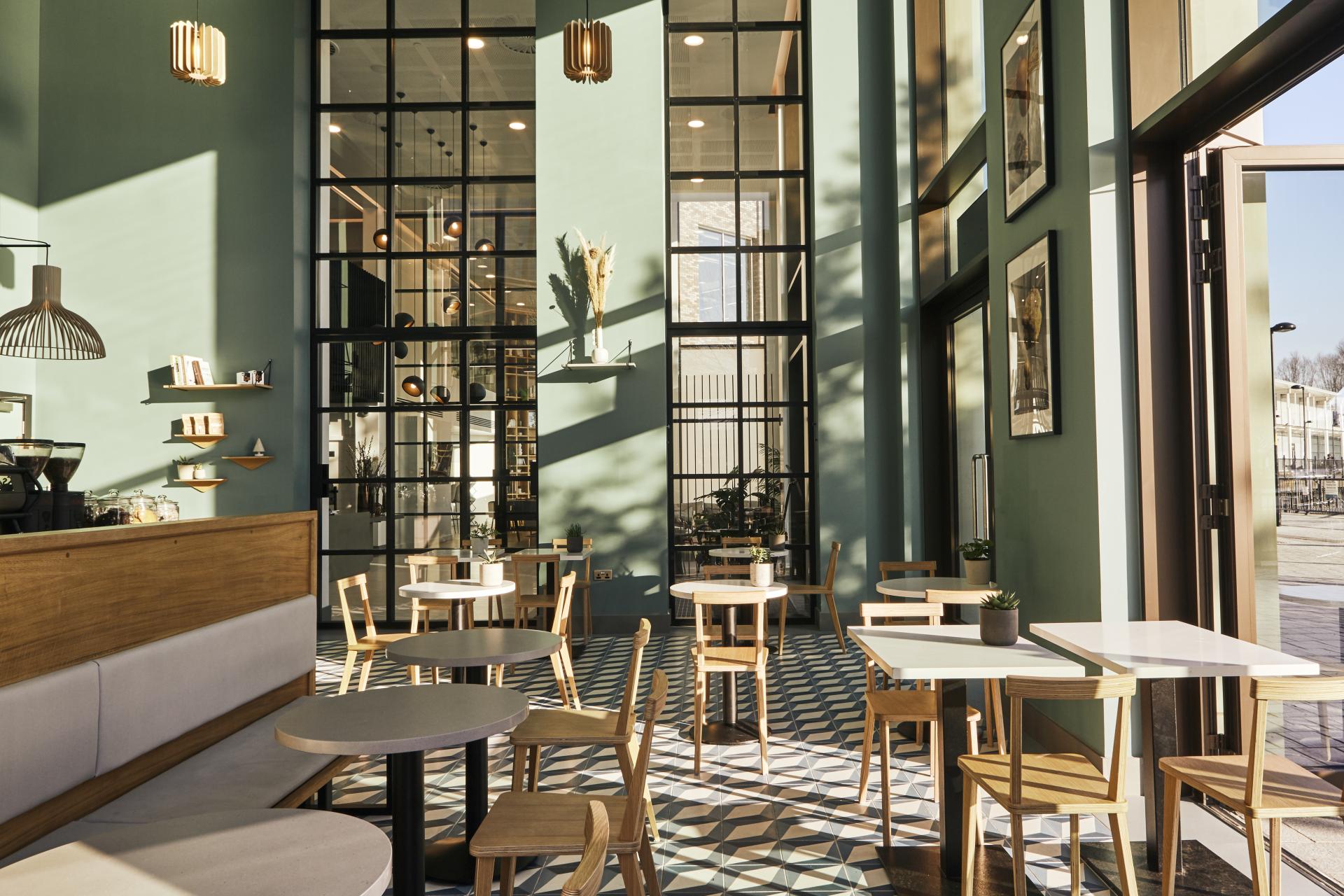 Chic coffee shop interior featuring Caesarstone quartz surfaces, sunlight flooding through large windows and stylish furnishings.