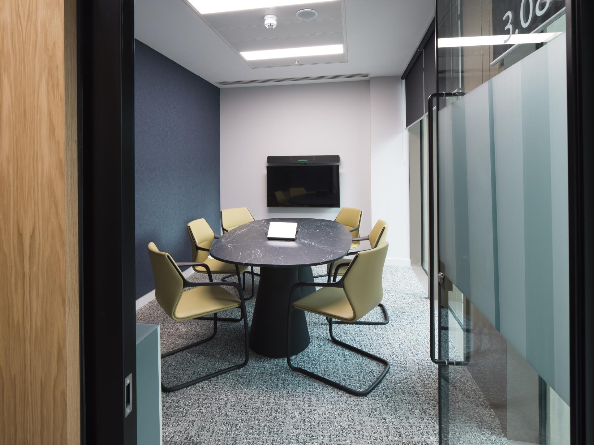 Modern conference room at the first WELL certified office in Scotland, featuring a round table and ergonomic seating.