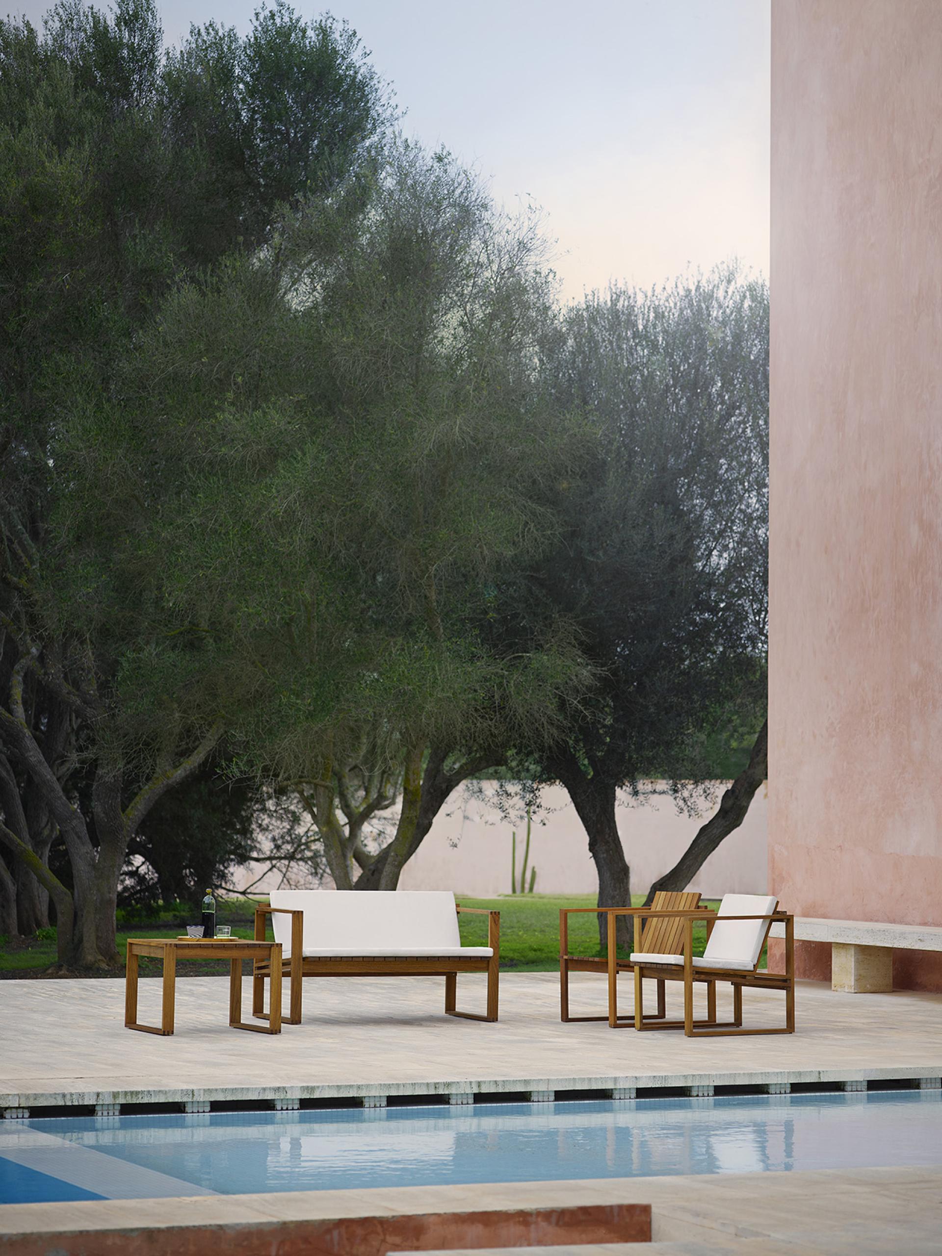 Elegant Bodil Kjær outdoor furniture set by Carl Hansen & Son, featuring a minimalist design by a poolside.
