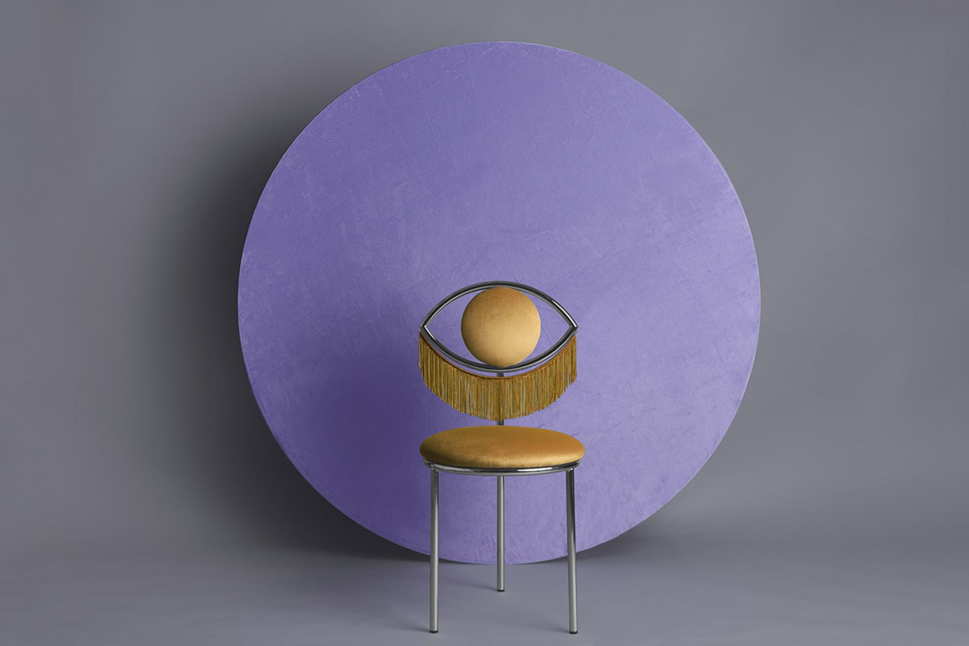 Wink chair by Masquespacio featuring a whimsical eye design, set against a purple circular backdrop.