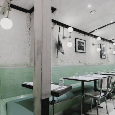 Art Deco interior of Lina Stores restaurant in Soho, featuring green and white striped decor, modern lighting, and seating arrangements.