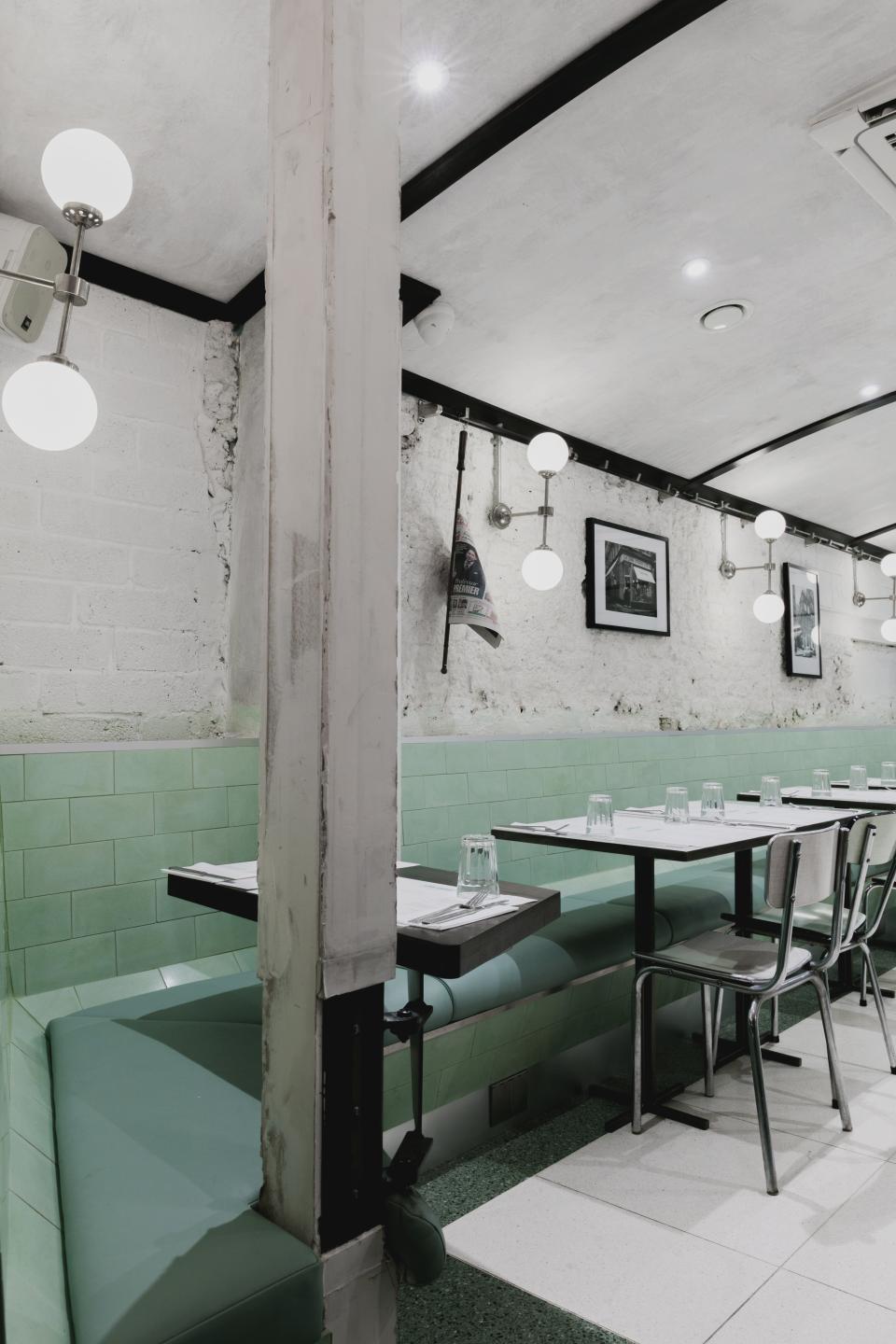 Art Deco interior of Lina Stores restaurant in Soho, featuring green and white striped decor, modern lighting, and seating arrangements.