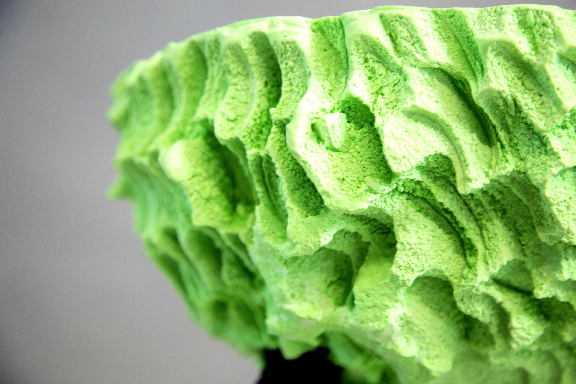 Textural green sculpture inspired by natural erosion, showcasing design influenced by wind, rain, and coastal landscapes.