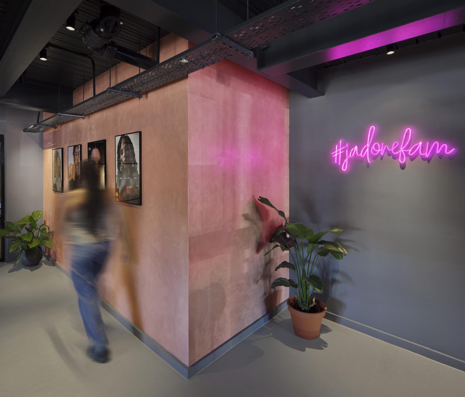 Stylish interior of J’adore Models HQ featuring a neon sign, artwork, and greenery, designed by Workshop Design Studio.