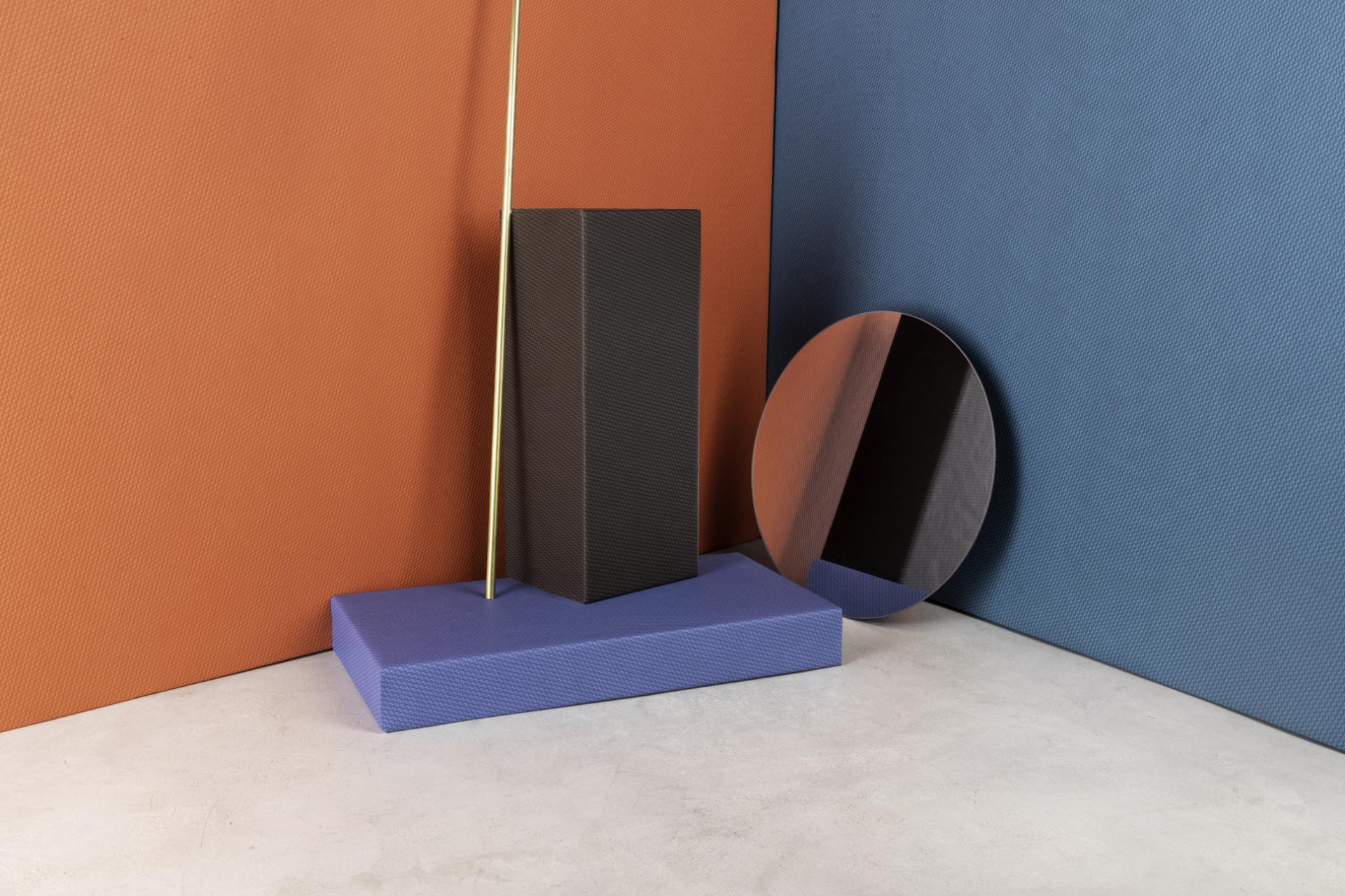 Textured performance textiles displayed on a minimalist platform against bold orange and blue backgrounds.