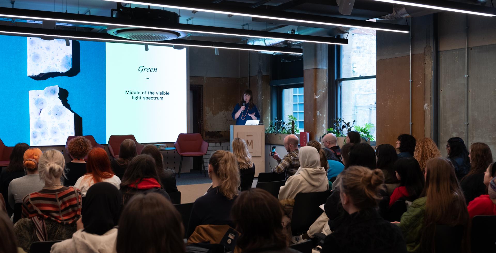 Laura Perryman presents on color theory to an engaged audience during a workshop at Manchester Metropolitan University.
