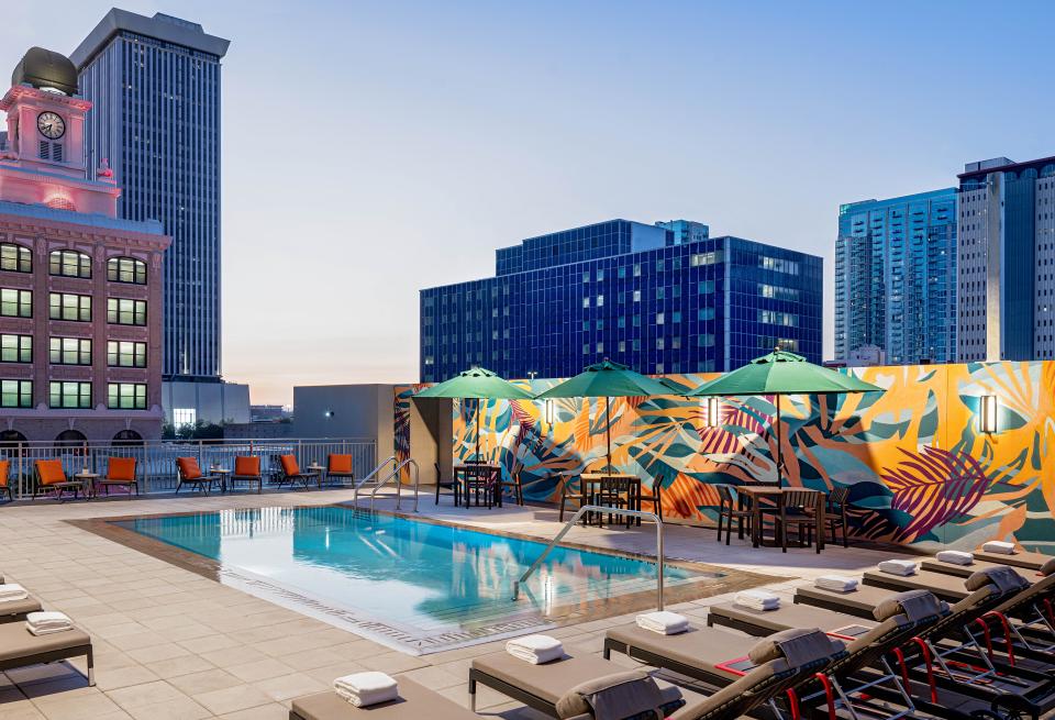 Rooftop pool area at Hyatt House Tampa featuring vibrant murals, lounge chairs, and city skyline views at dusk.