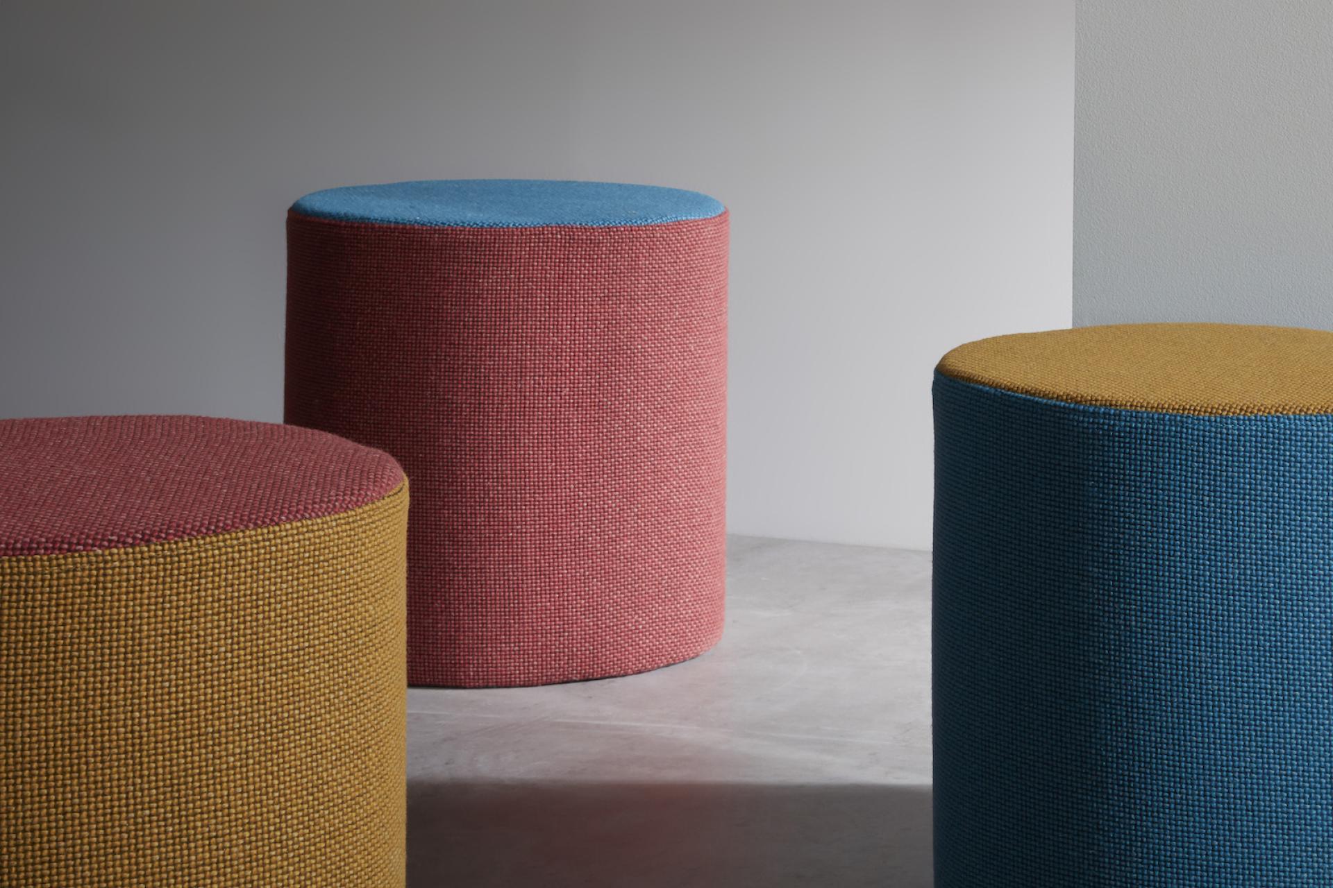 Colorful, textured stools upholstered in Camira's sustainable Craggan Flax, showcasing a blend of eco-friendly materials.