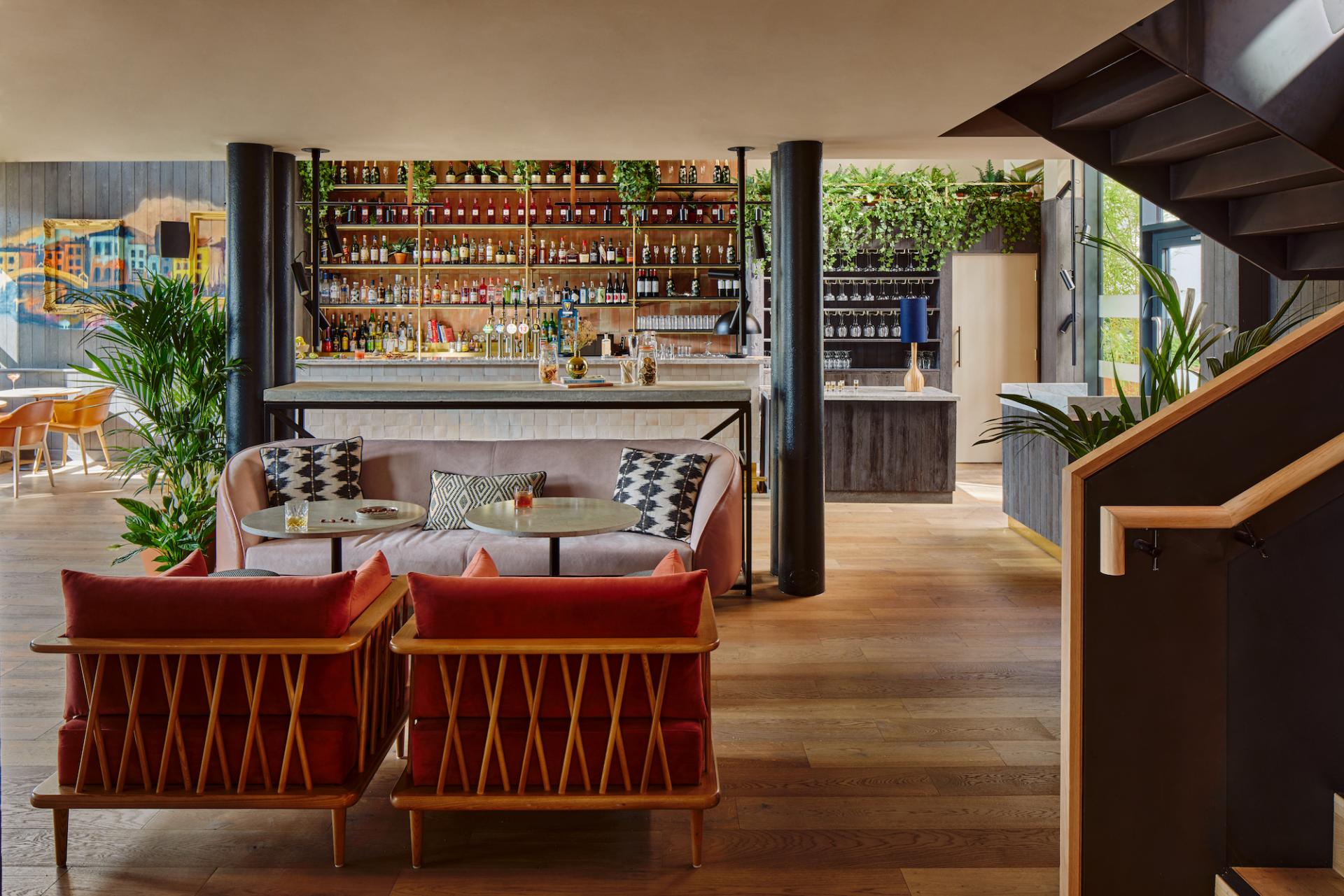 Stylish lounge area in Zanzibar Locke aparthotel featuring retro decor, vibrant greenery, and a well-stocked bar.