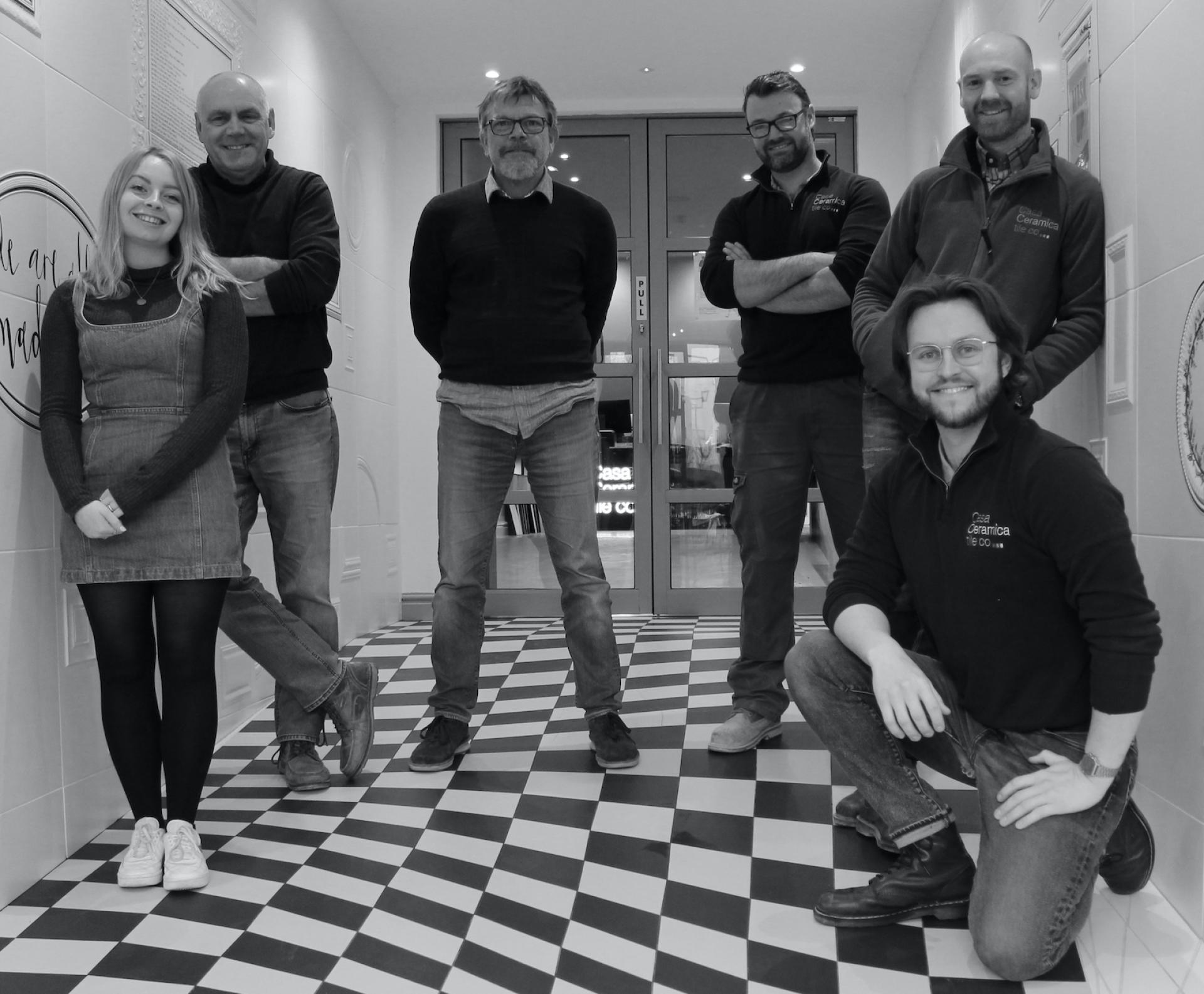 Team of Casa Ceramica members standing together in a stylish showroom, showcasing contemporary design and community spirit.
