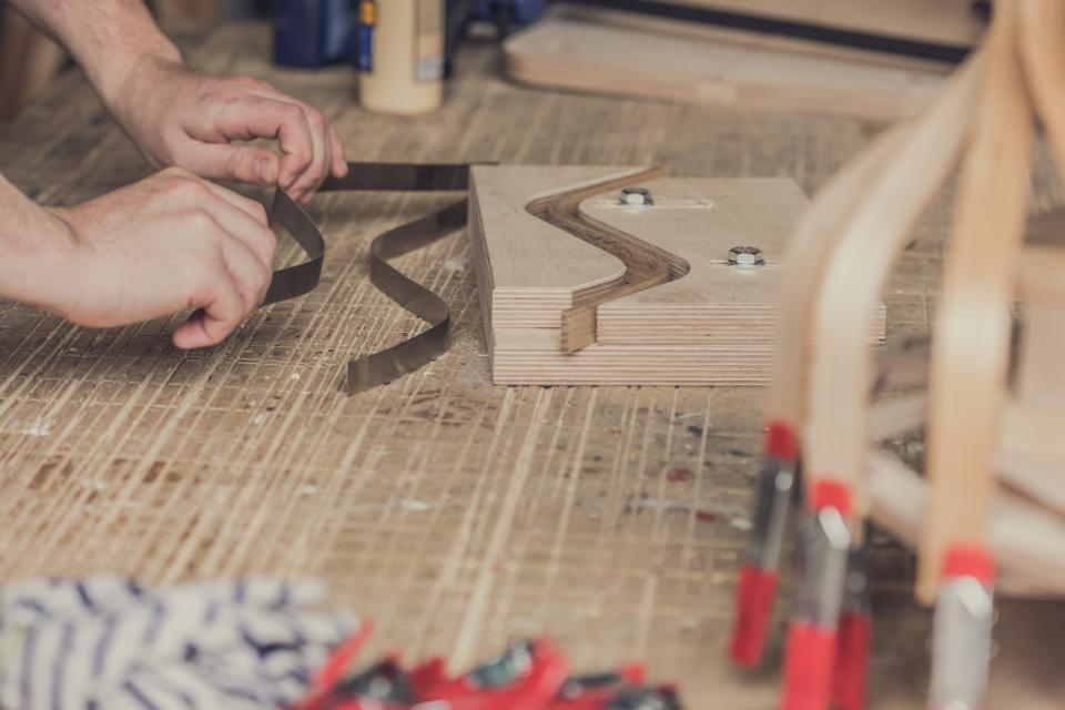 Craftsman shaping materials for bespoke lampshades inspired by art deco design in a woodworking workshop.