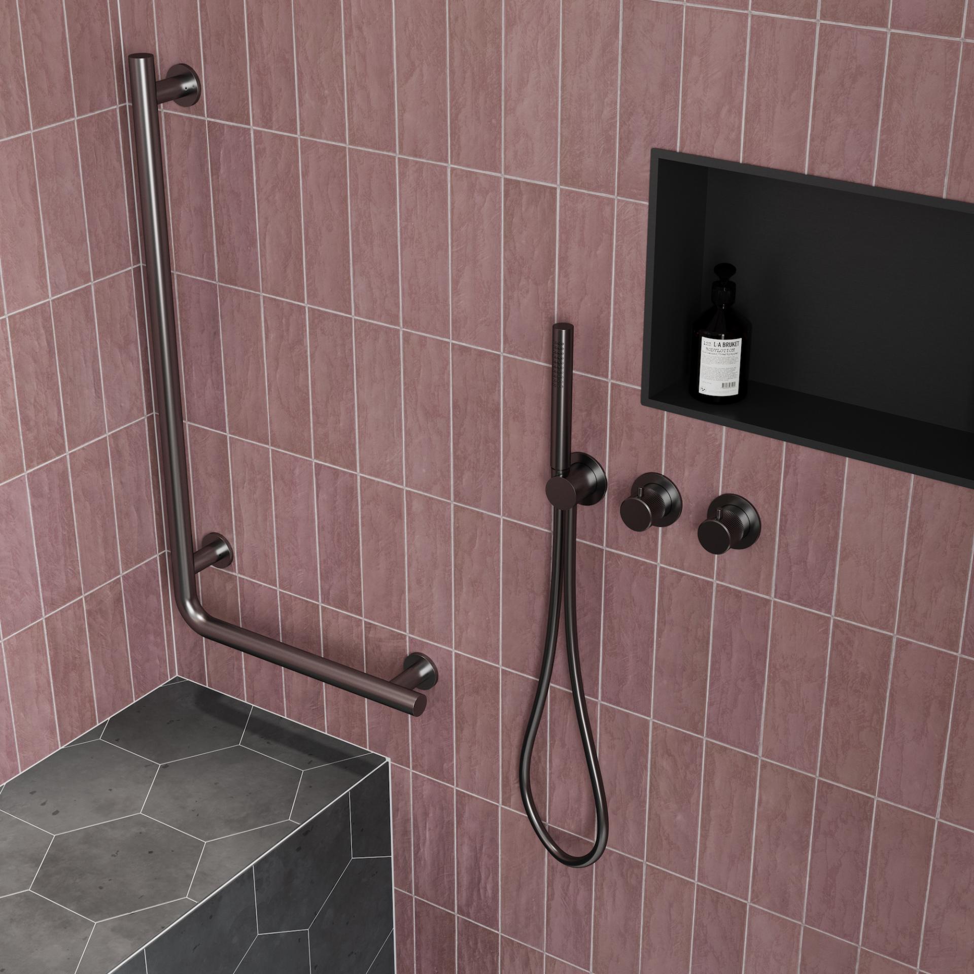 Stylish bathroom shower set featuring pink tiles, a grab bar, and sleek black fixtures for safety and design.
