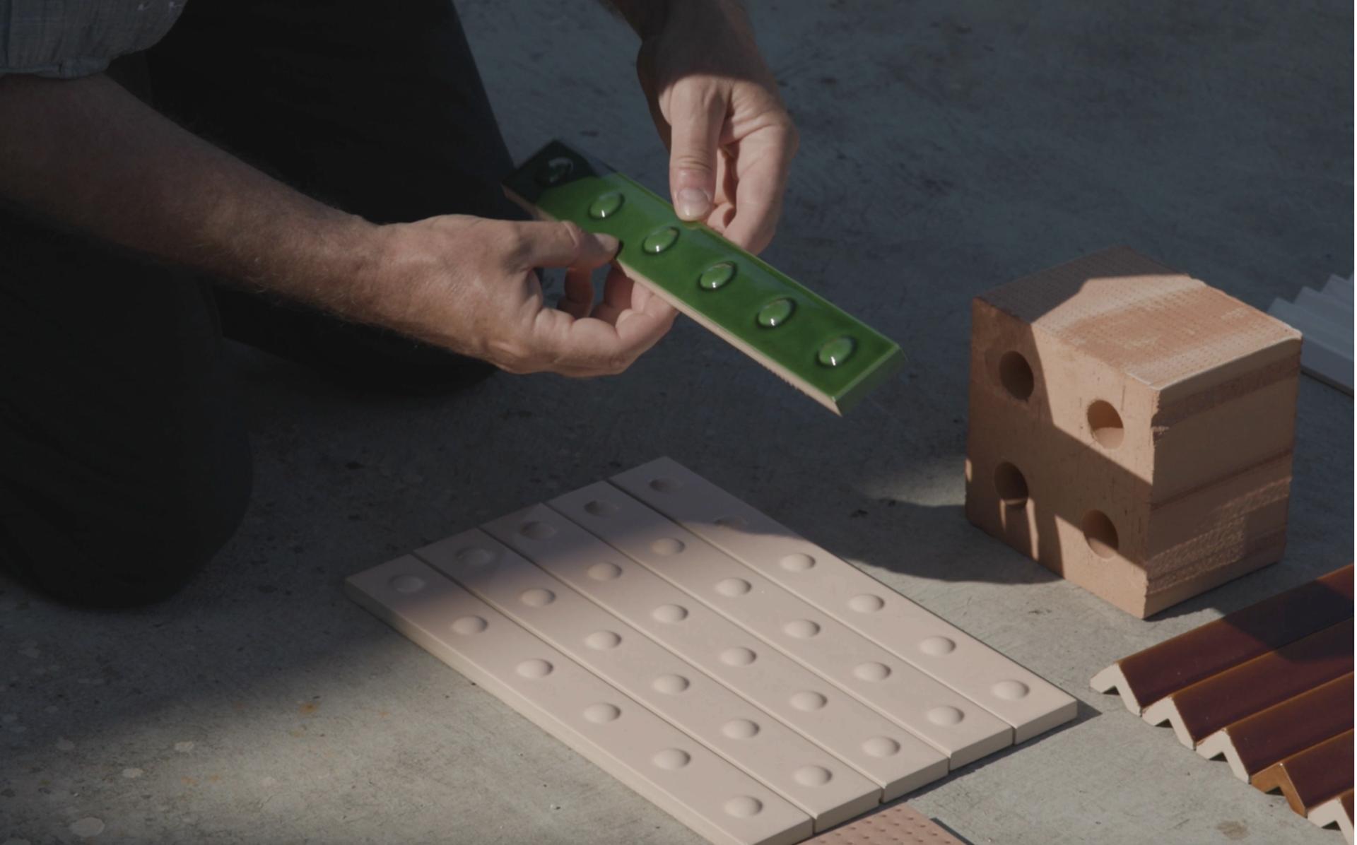 Hands arranging ceramic tiles and bricks, showcasing materials from the collaboration between Mutina and Studio Bouroullec.
